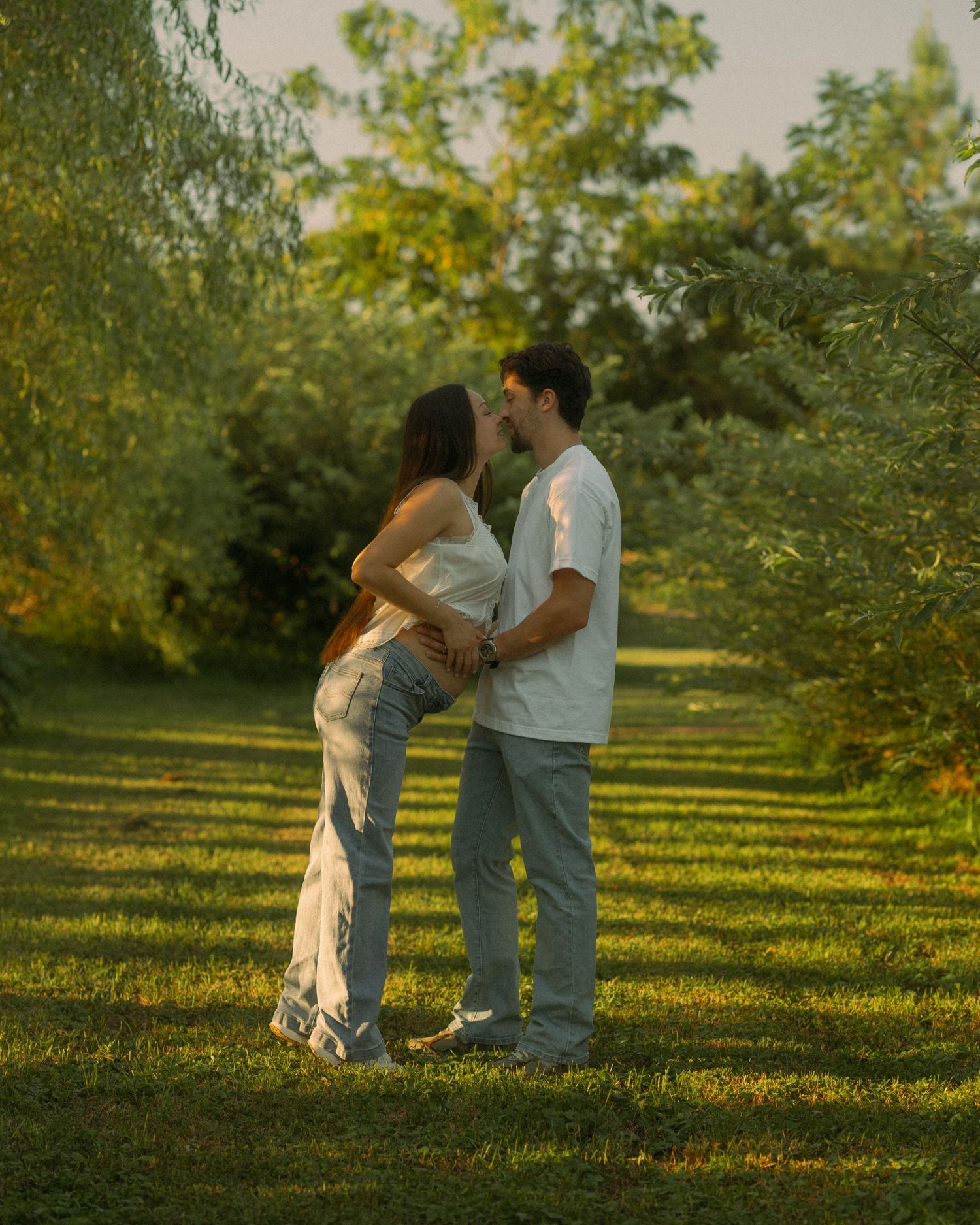 A young couple expecting their first child, they embrace the soon-to-be-mother's pregnant belly while going in for a kiss. Nokesville, VA