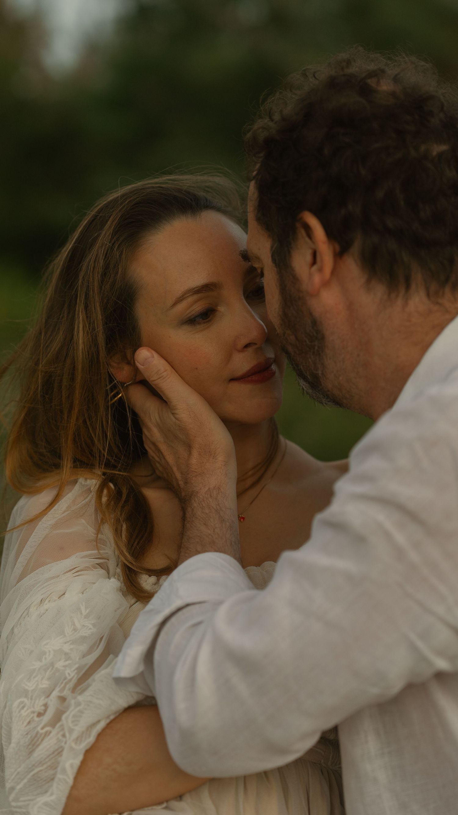 a woman looking lovingly into her husband's face while he gently caresses her face
