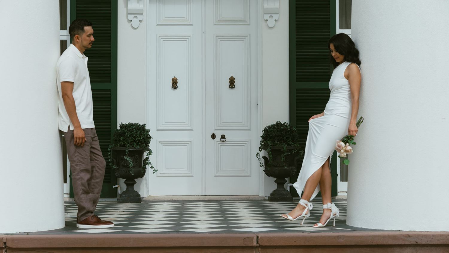 Minimalist white hallway with people walking on checkered floor tiles.