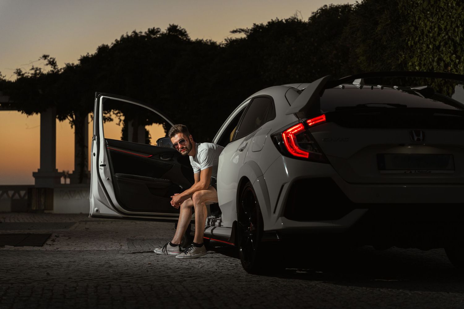 Silhouetted automotive photography scene at dusk with dramatic lighting.