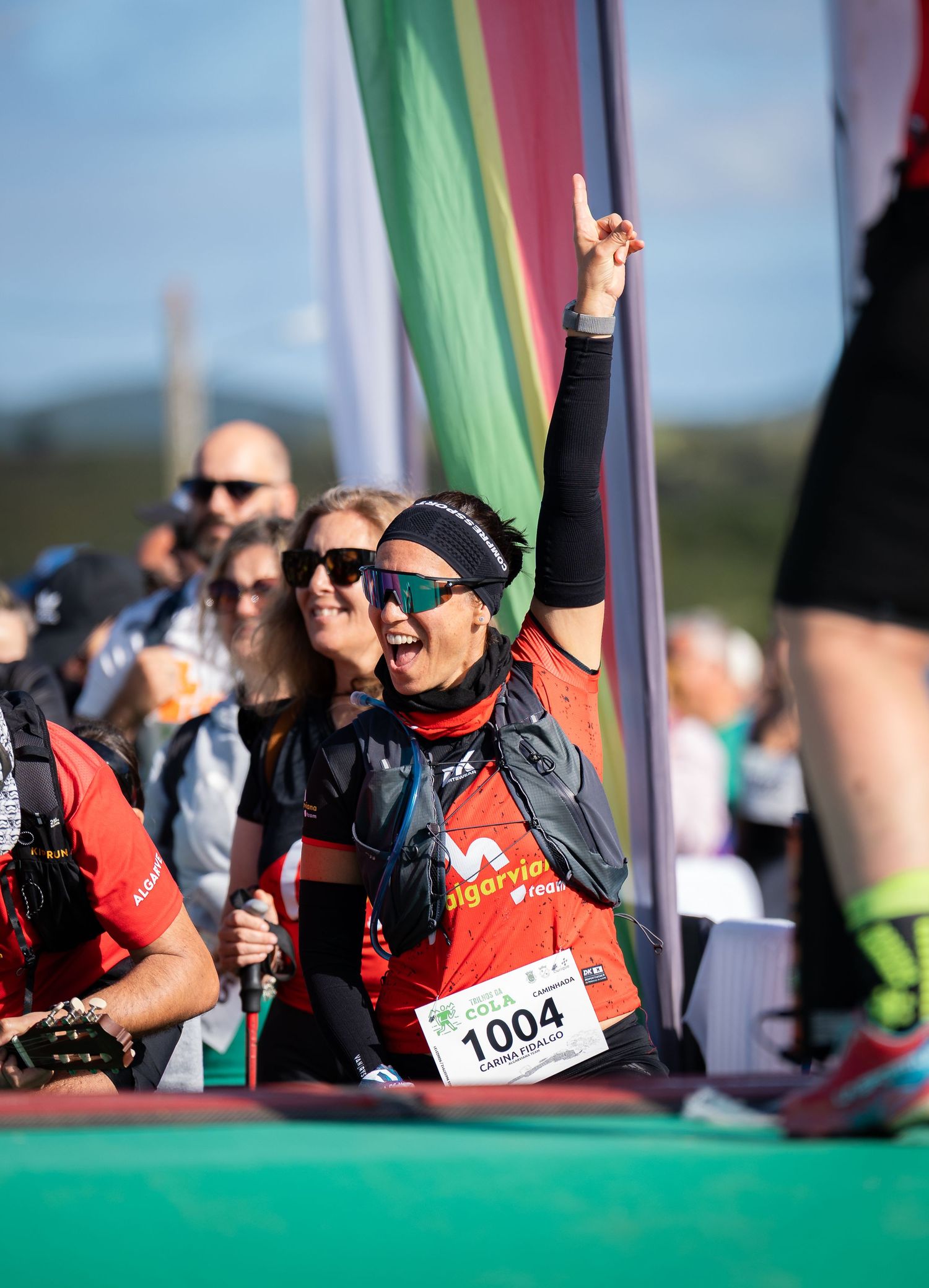 Enthusiastic runner in red jersey celebrates at race event with crowd.