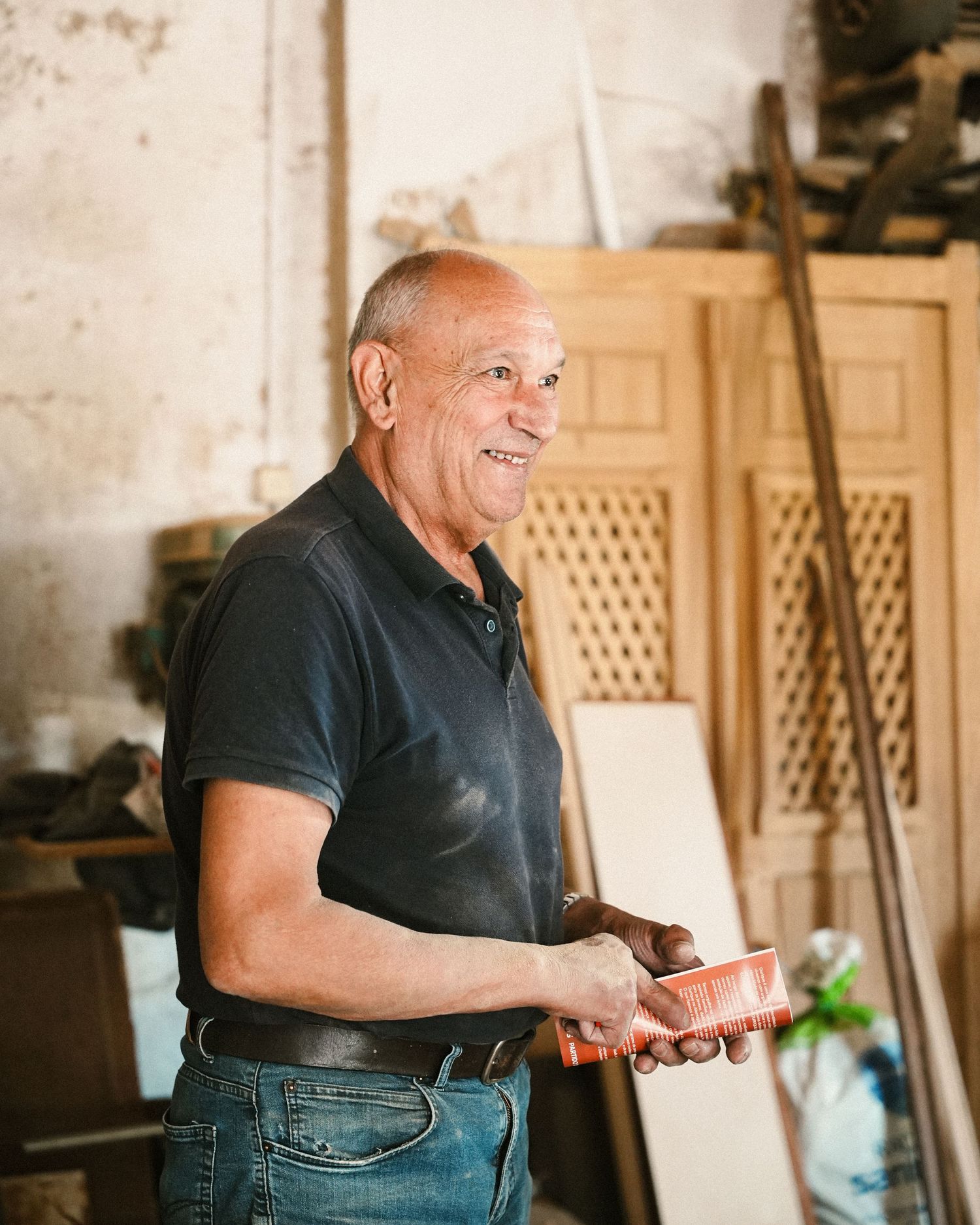 Person in black shirt smiling while working in a workshop setting.