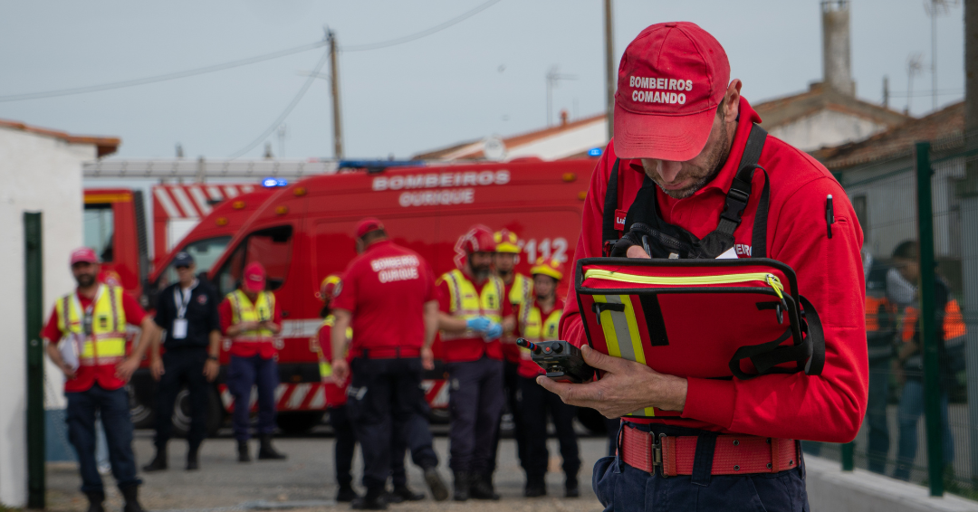 Emergency responder in red uniform reviews documents during outdoor operation.