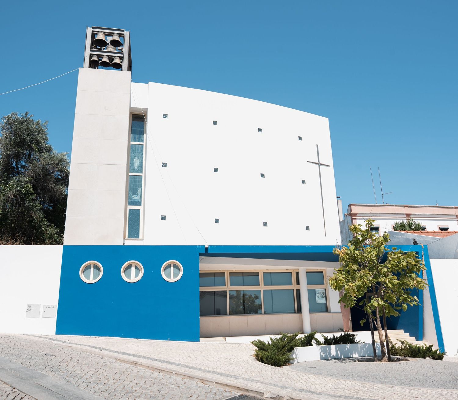 Modern white and blue church building with geometric design against clear sky.