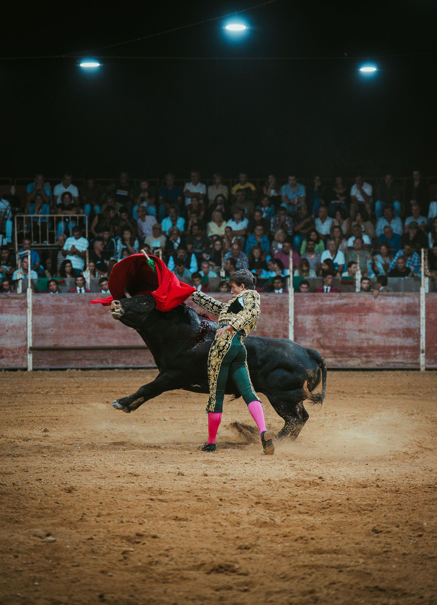 A sequence of action shots showing a bullfighter performing acrobatic flips over a charging bull in a sandy arena.
