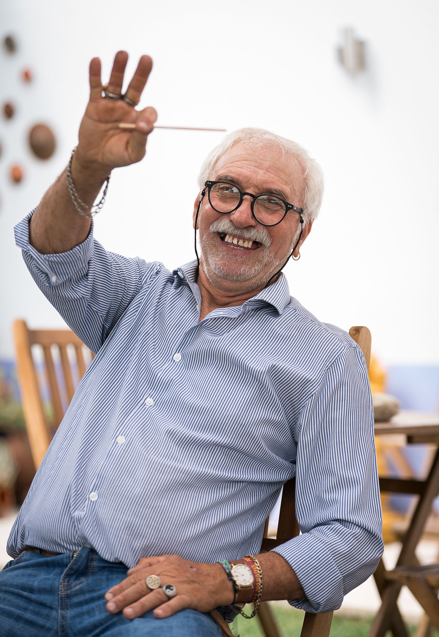Senior guest in striped shirt expressing joy with animated gestures at outdoor event.