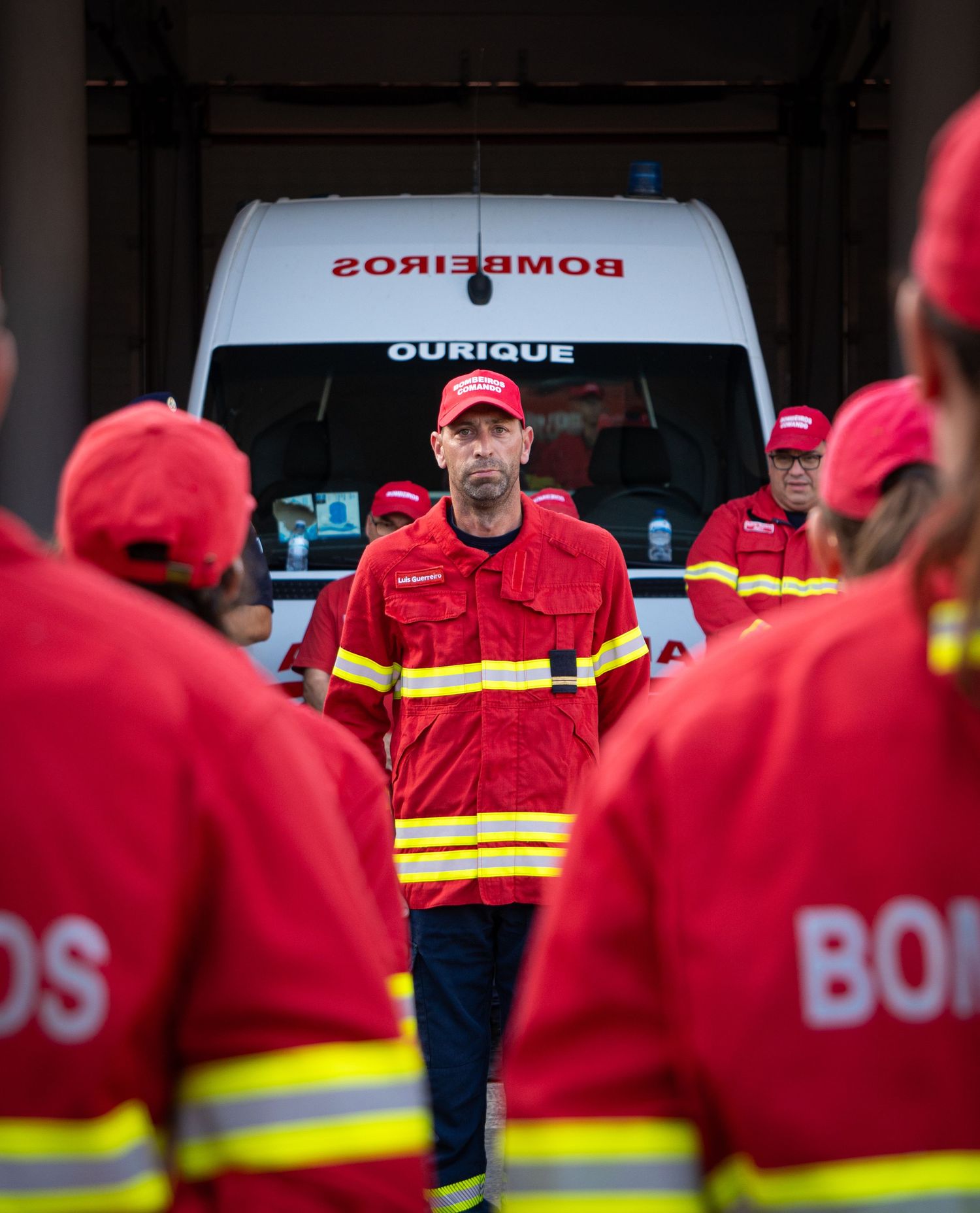Firefighters in red uniforms gathered around emergency vehicles during a training session.