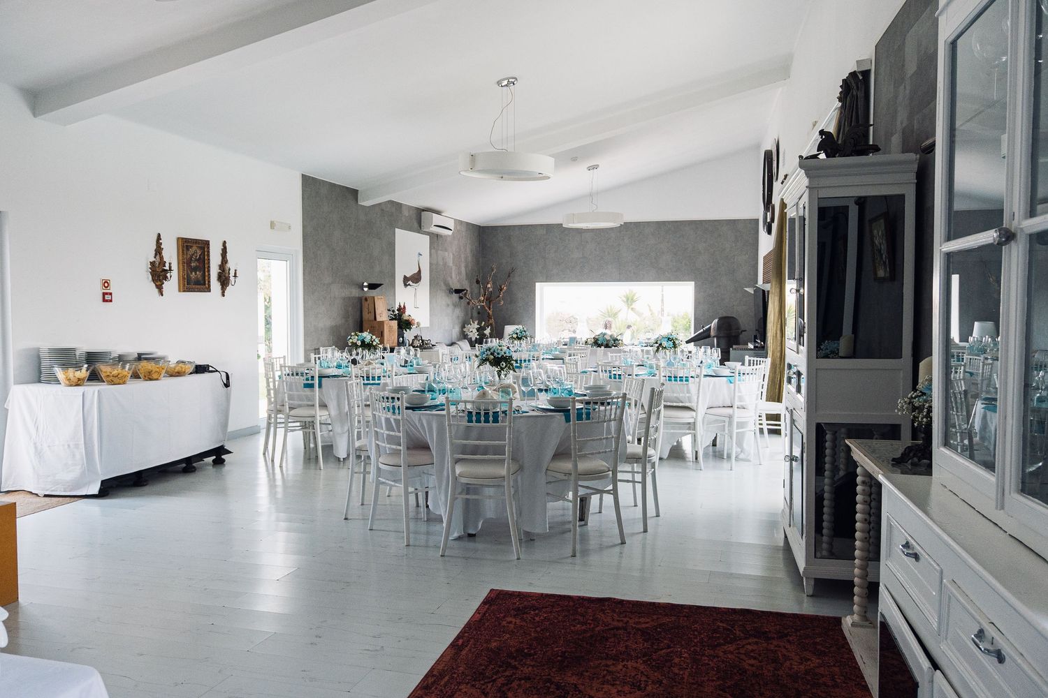Modern white reception venue with sleek tables and chairs arranged for an event.