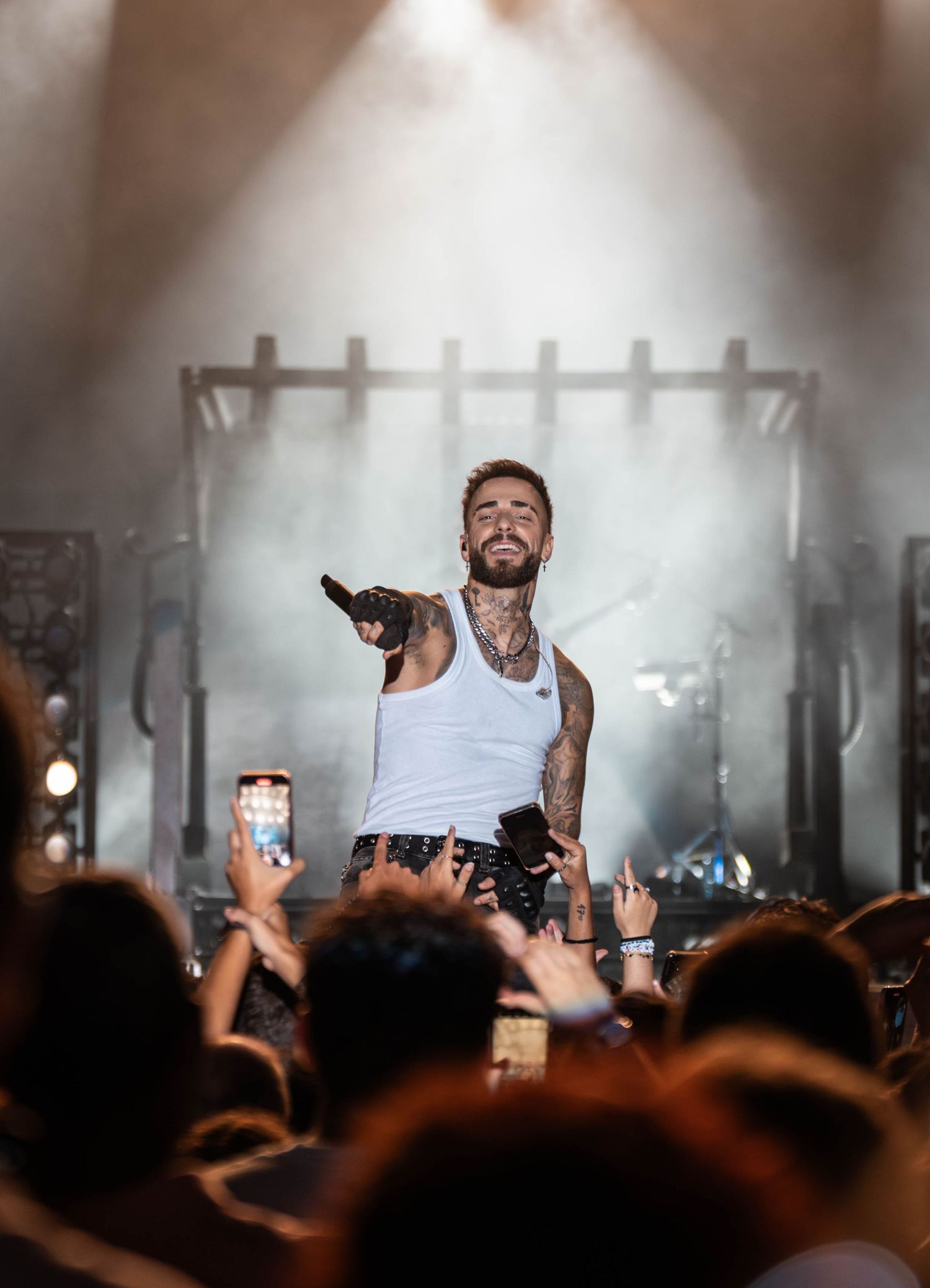 Concert crowd with raised phones and hands during dramatic stage performance.