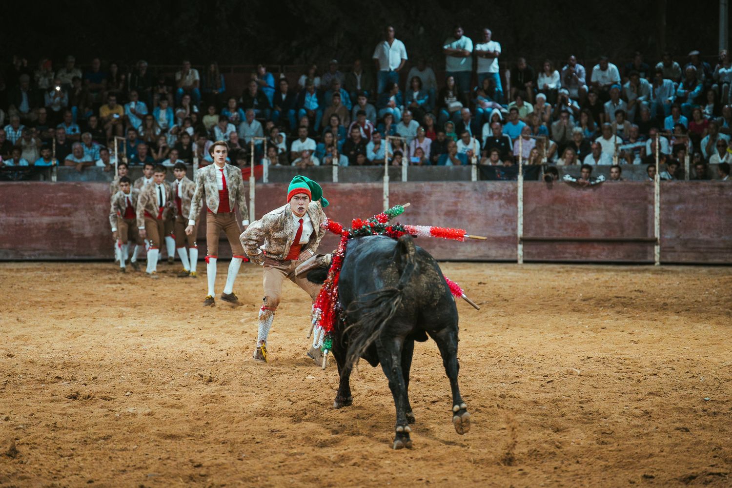 Panoramic view of a bullfighting arena during an evening performance with crowds in attendance.
