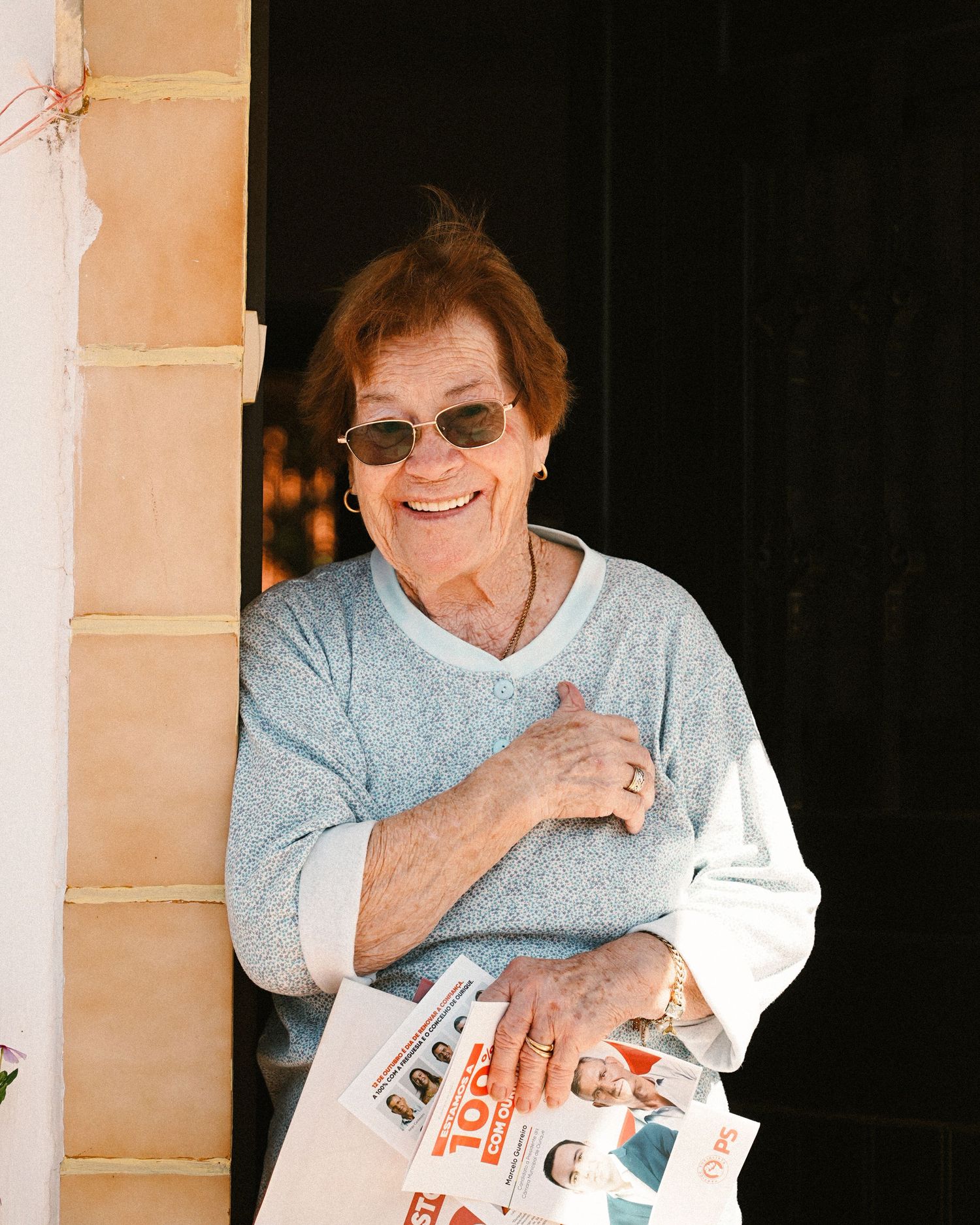 Person in light blue sweater smiling while holding papers.