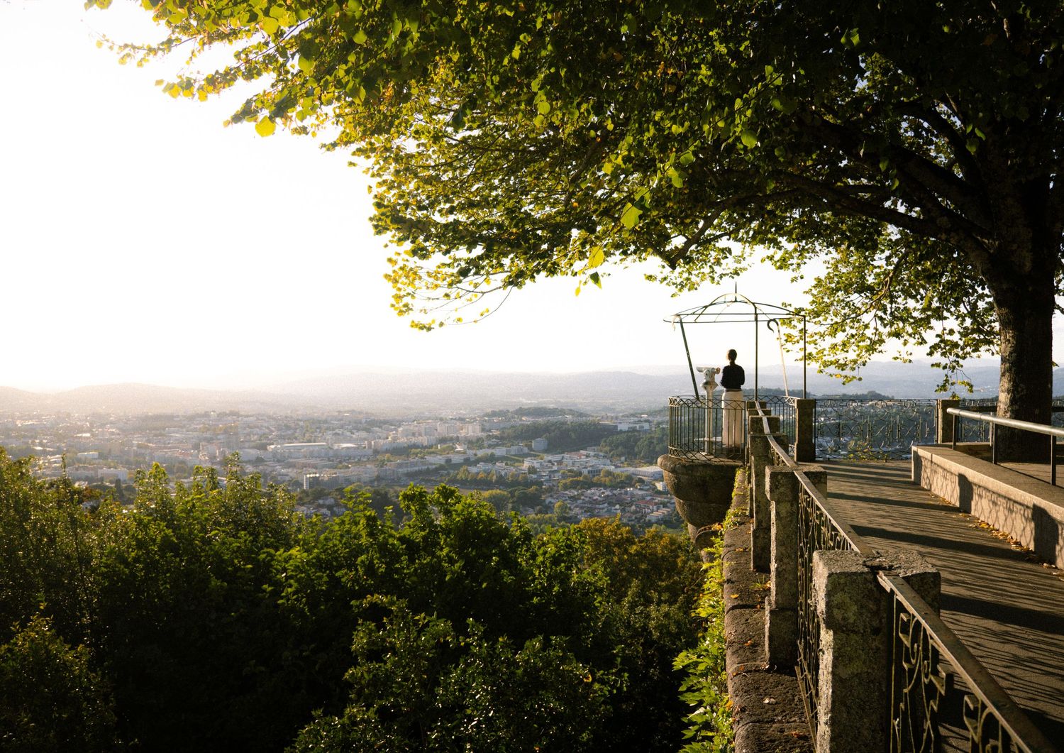 Wooden observation deck overlooking expansive city valley at sunset.