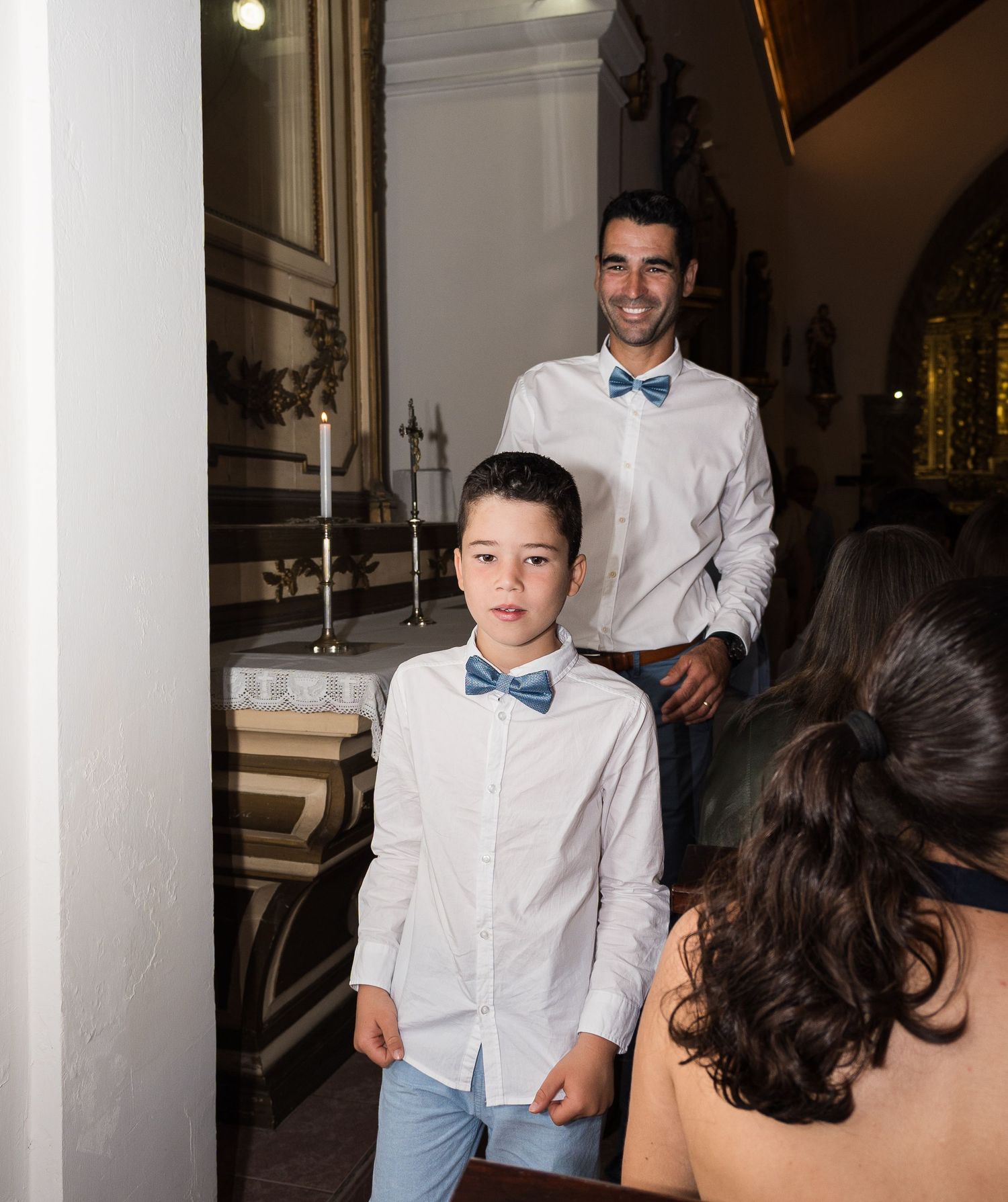 People in formal white shirts and blue bow ties posing in elegant interior setting.