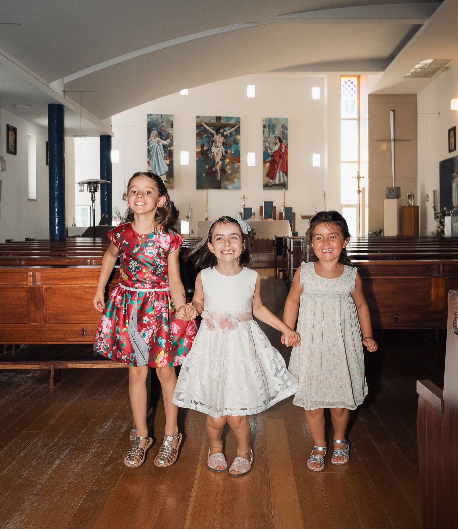 People in formal attire stand together in a church with wooden pews.