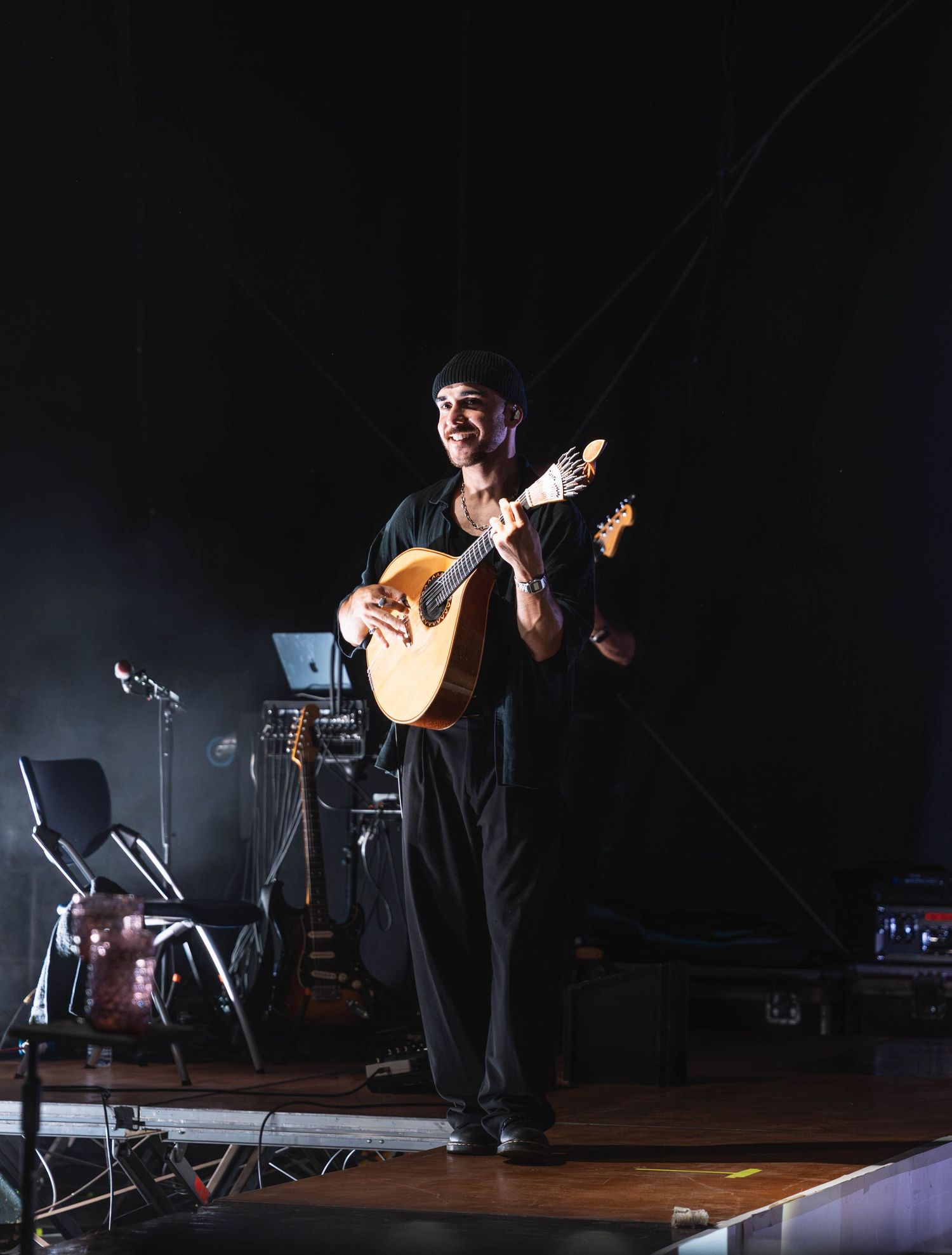Solo performer on dark stage with musical equipment and dramatic backlighting.