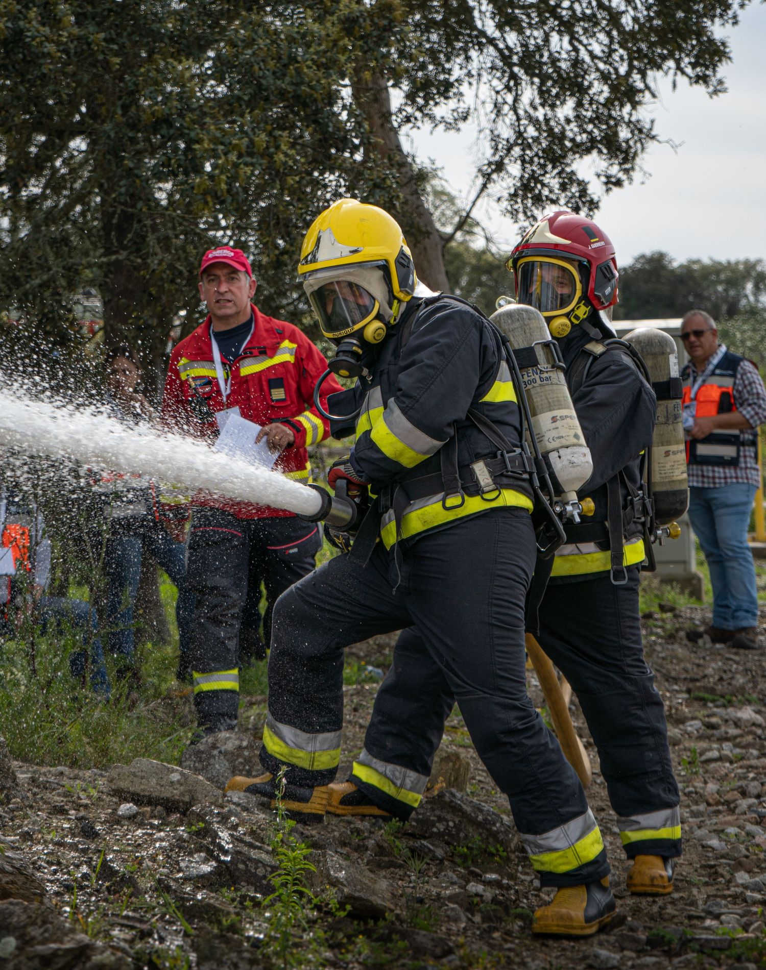 Firefighters in protective gear operate water hose during training or emergency response.