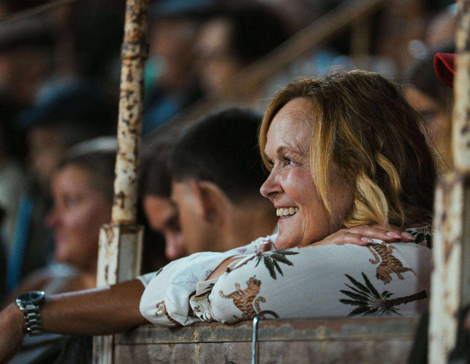 Baseball fans lean over railing at stadium watching game with excited expressions during sporting event.