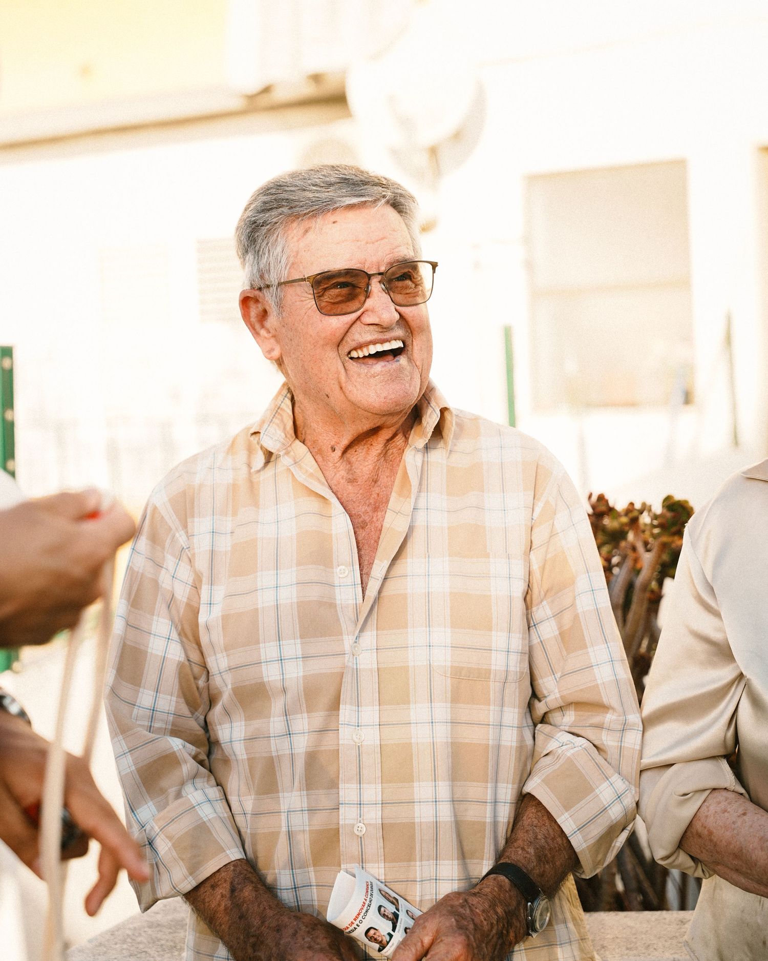 Series of photos showing senior man in plaid shirt laughing during outdoor gathering.