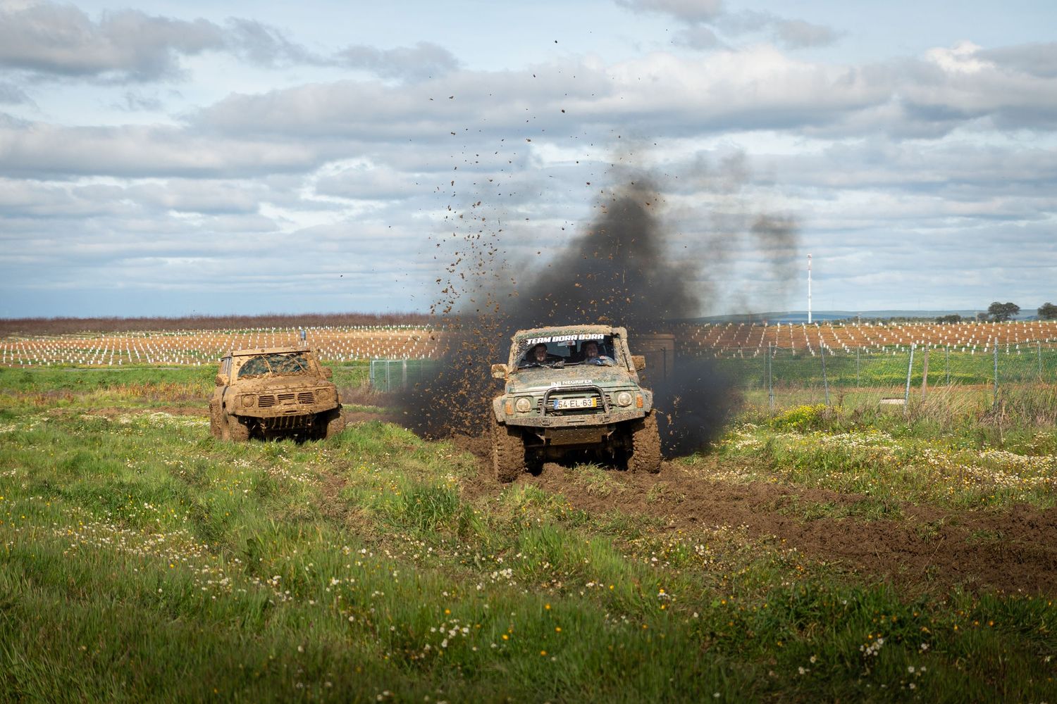 Sequence of military vehicles burning in a grassy field with black smoke rising against a cloudy sky.
