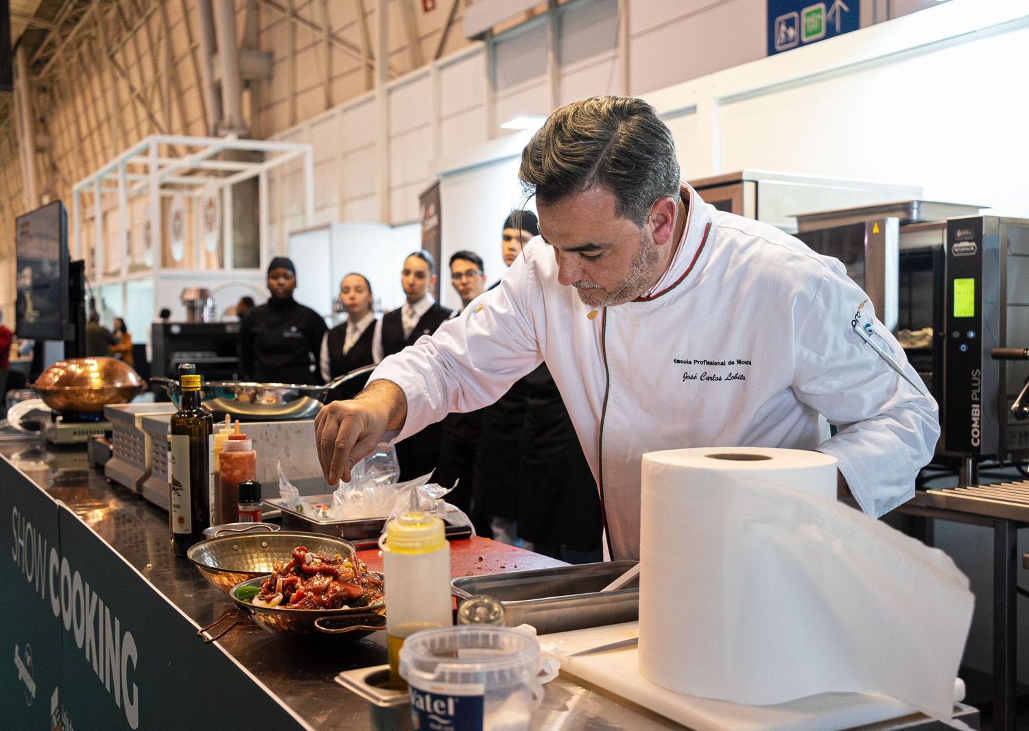 Chefs working in professional kitchen preparing food at stainless steel counters.