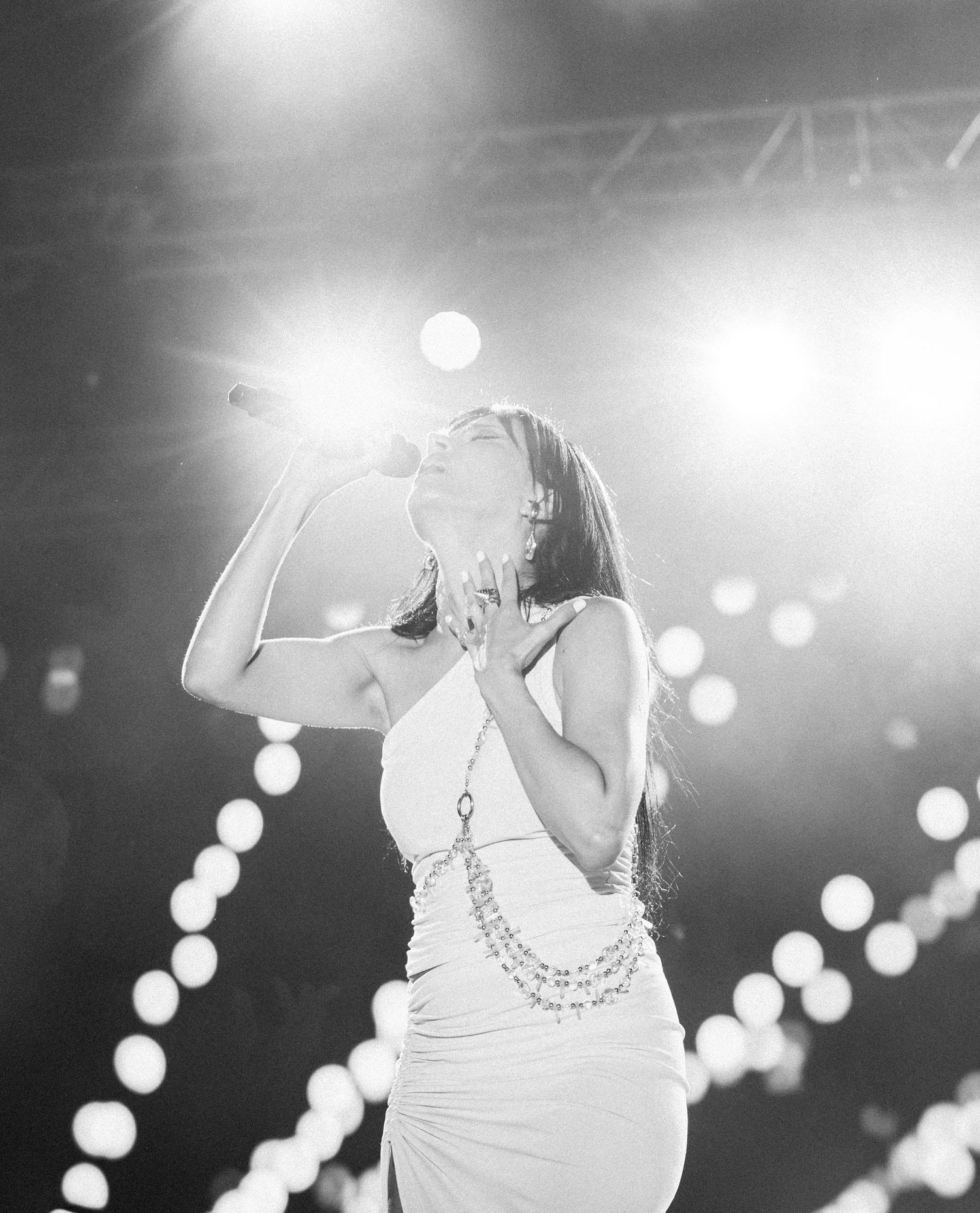 Black and white performance shot with bokeh lights creating dreamy atmosphere.