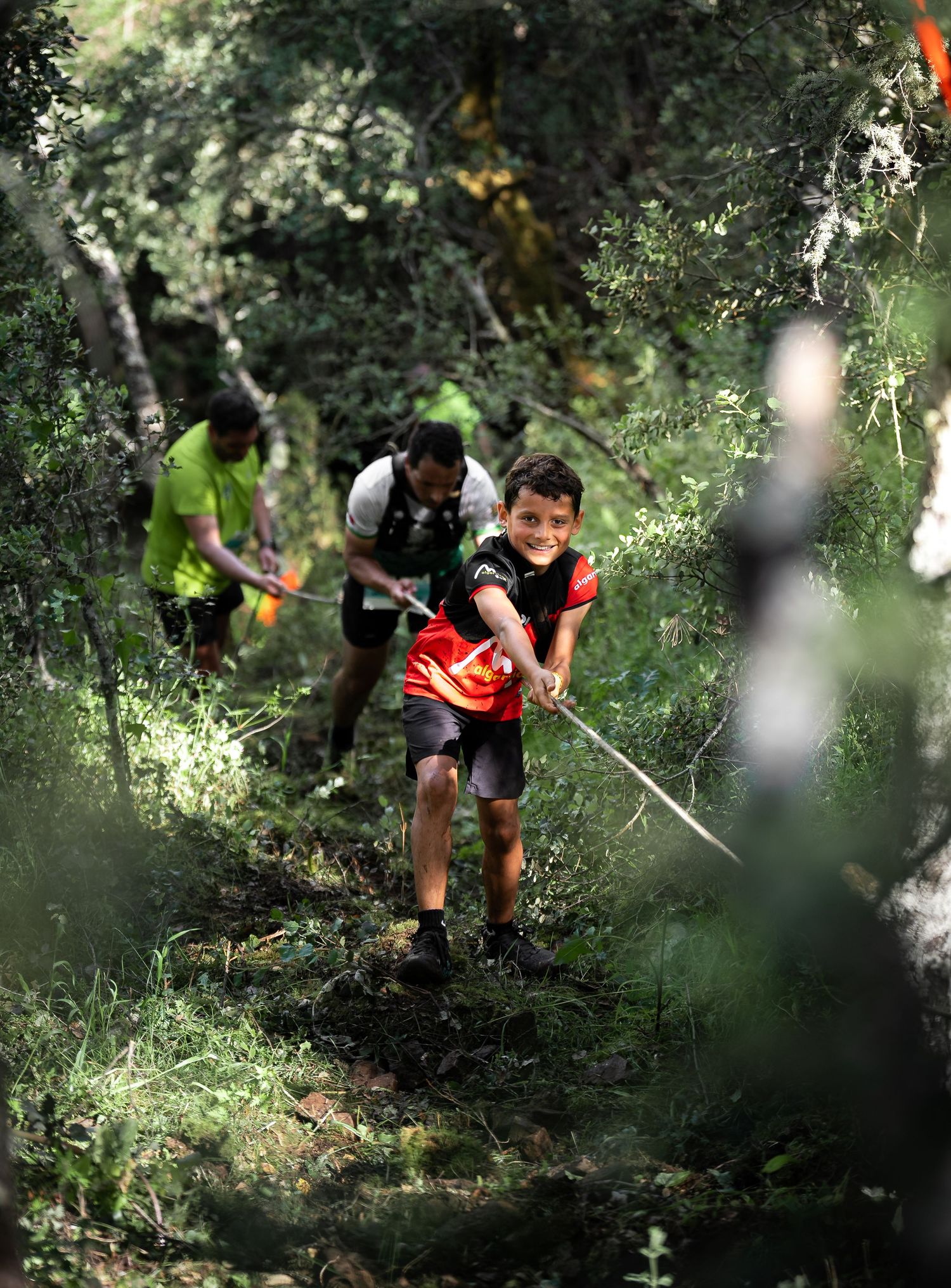 Athletes descending steep forest trails during an intense outdoor competition.