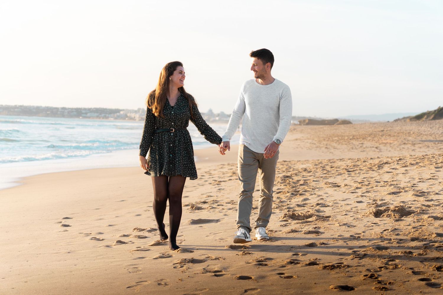 A couple walks along a scenic beach during sunset.