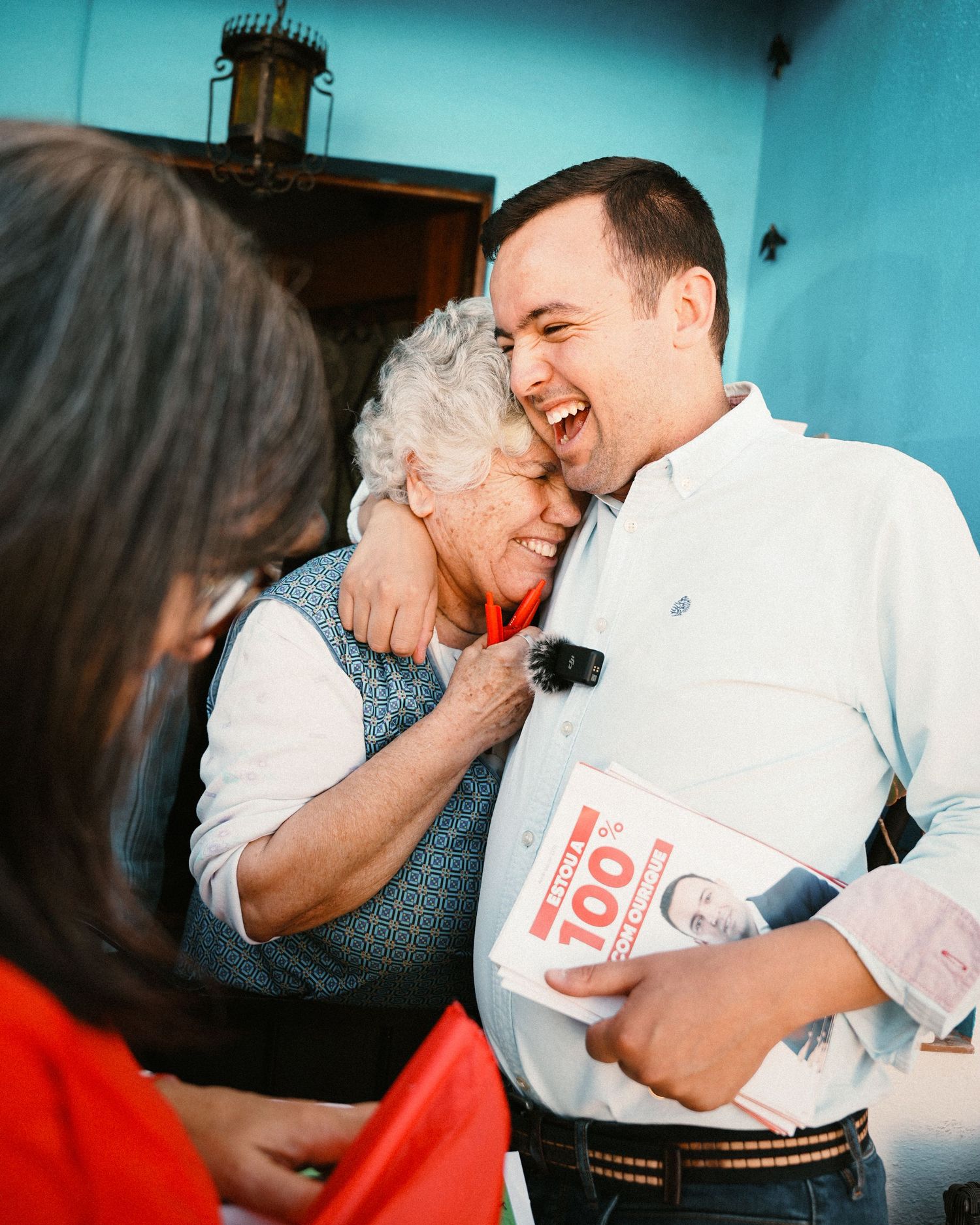 People embracing and laughing together in a room with blue walls.