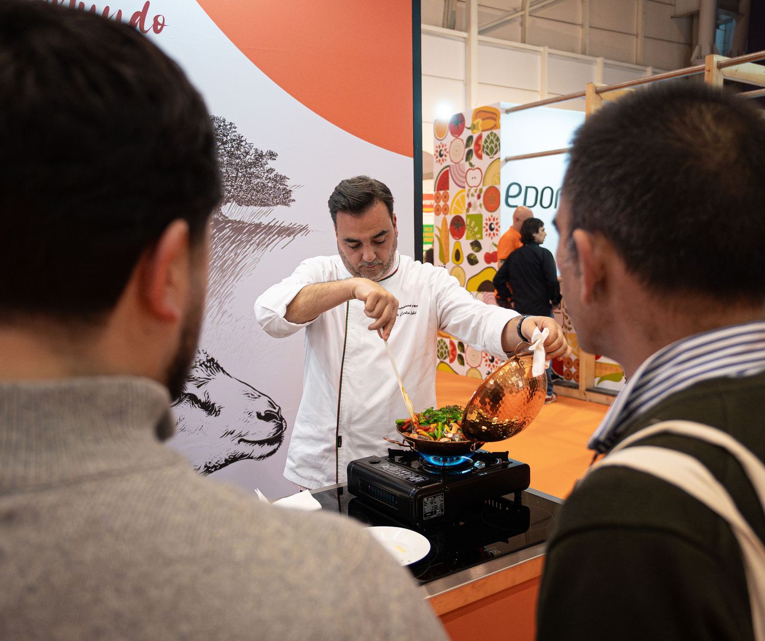 Chef demonstrating culinary techniques at a food exhibition booth.