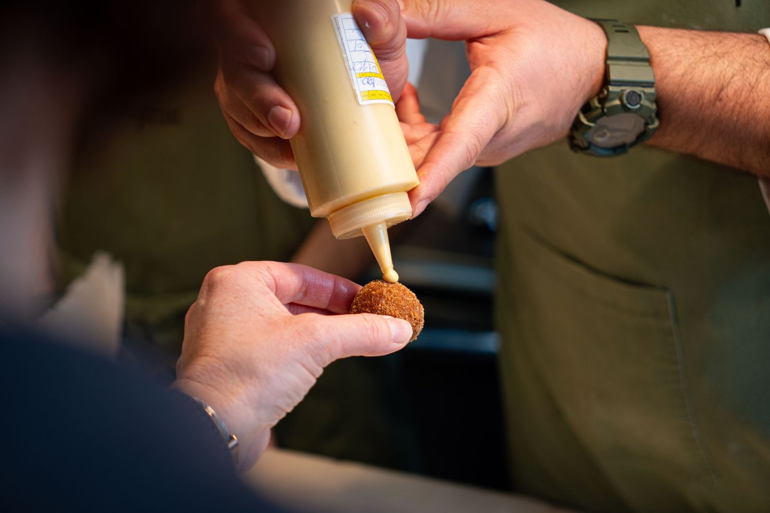 Close-up of hands piping sauce or cream from pastry bag.