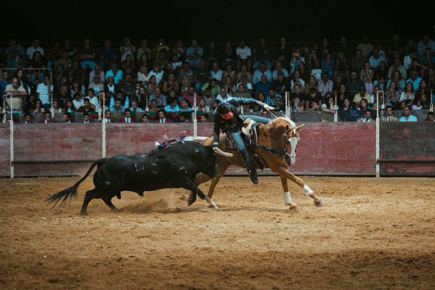 Dramatic sequence of a bull charging at a bullfighter in an arena with spectators watching from the stands.