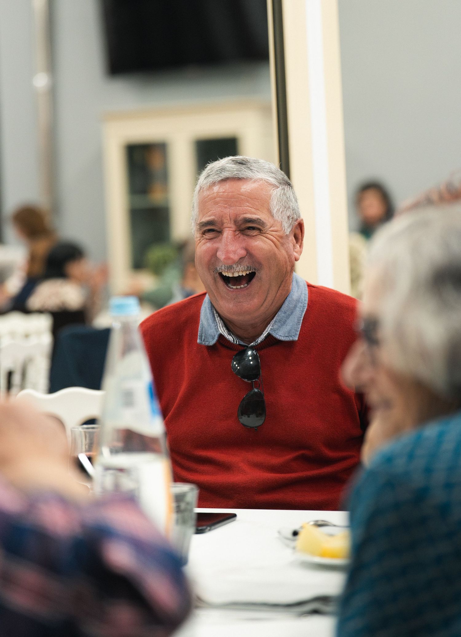 Individual in red sweater displaying genuine laughter during a social gathering.