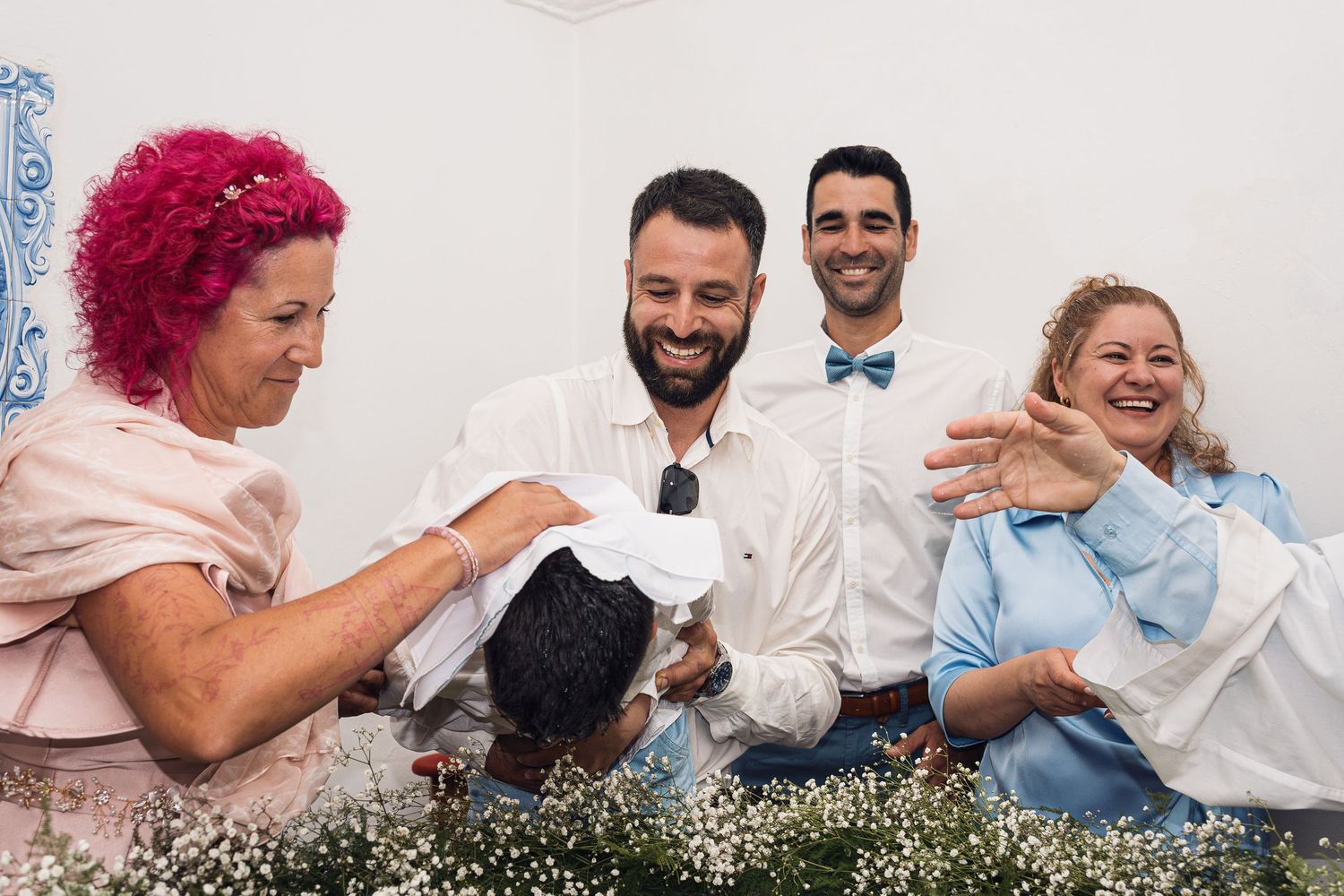 Candid family moments captured against white backdrop with floral decorations.