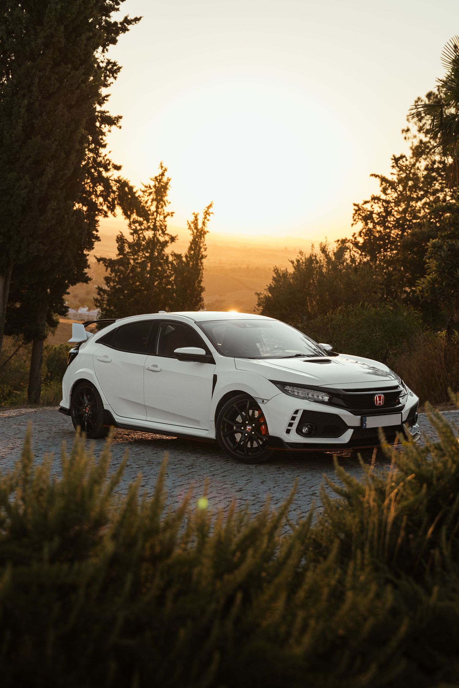 White Honda Civic Type R photographed at sunset with dramatic lighting and natural scenery.