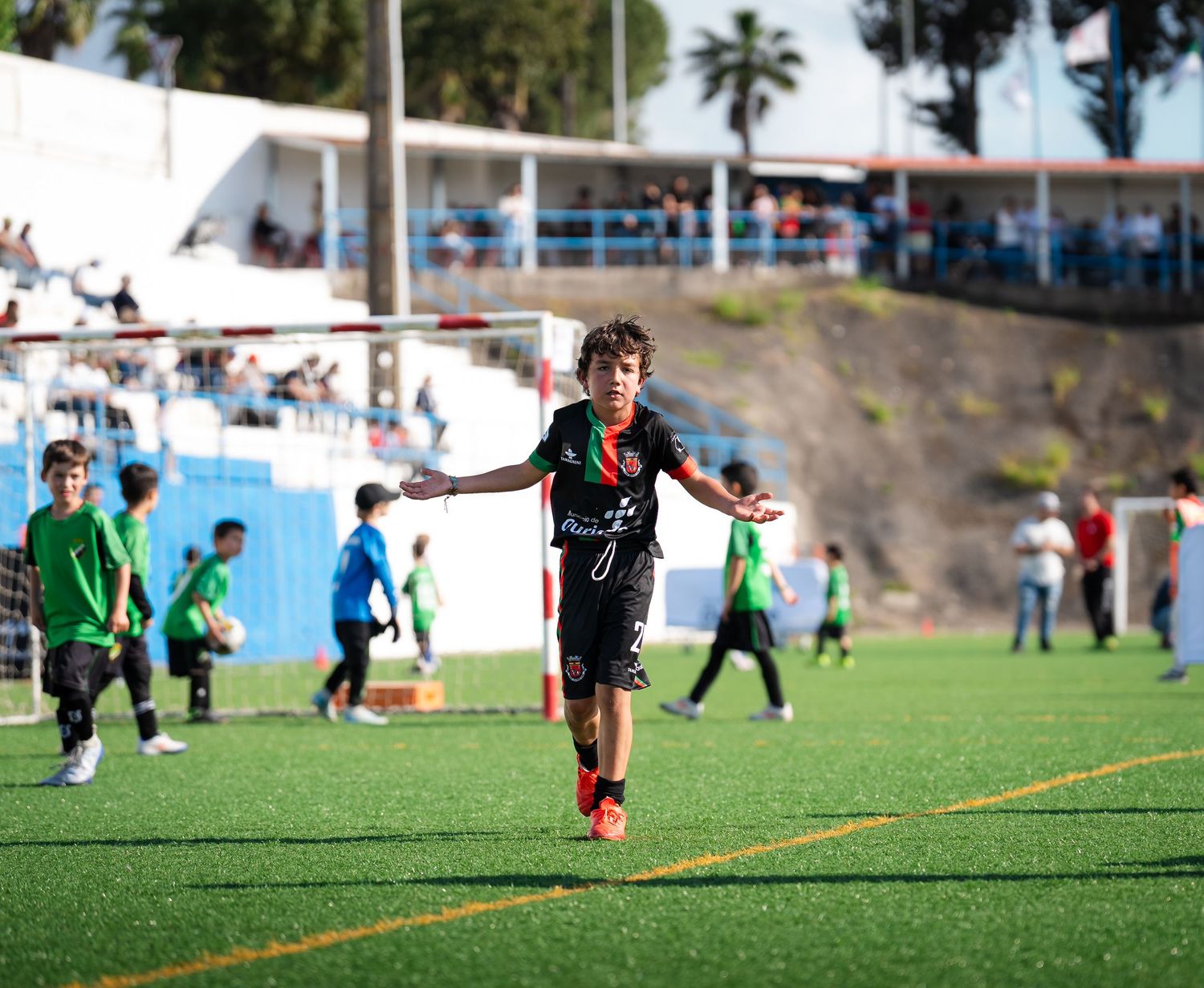 Soccer players practicing drills on grass field with palm trees in background.