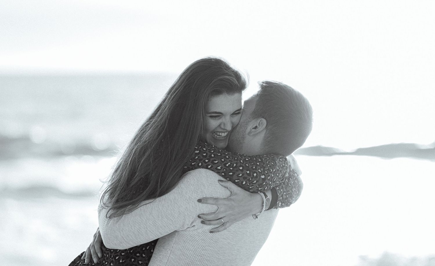 A tender moment shared between people on a misty beach.