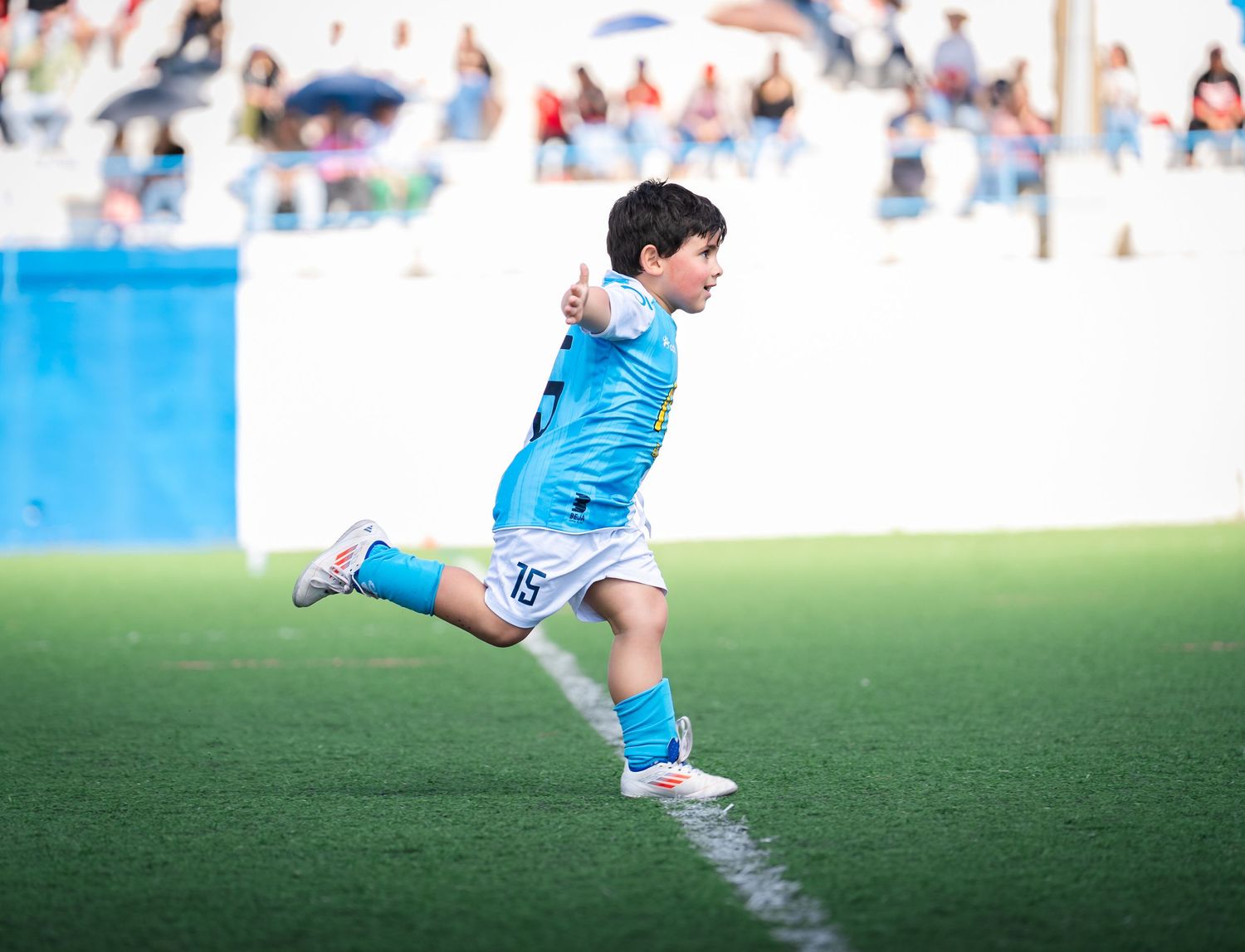 Player in light blue uniform runs energetically during soccer match.