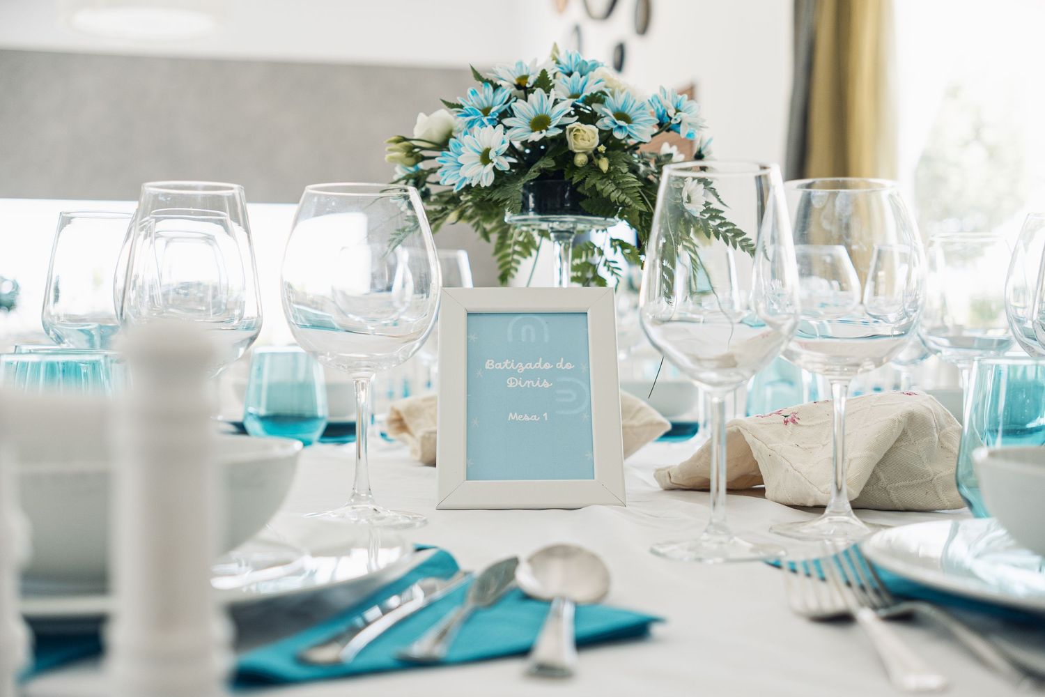 Elegant wedding reception tables decorated in turquoise and white with floral centerpieces and place settings.