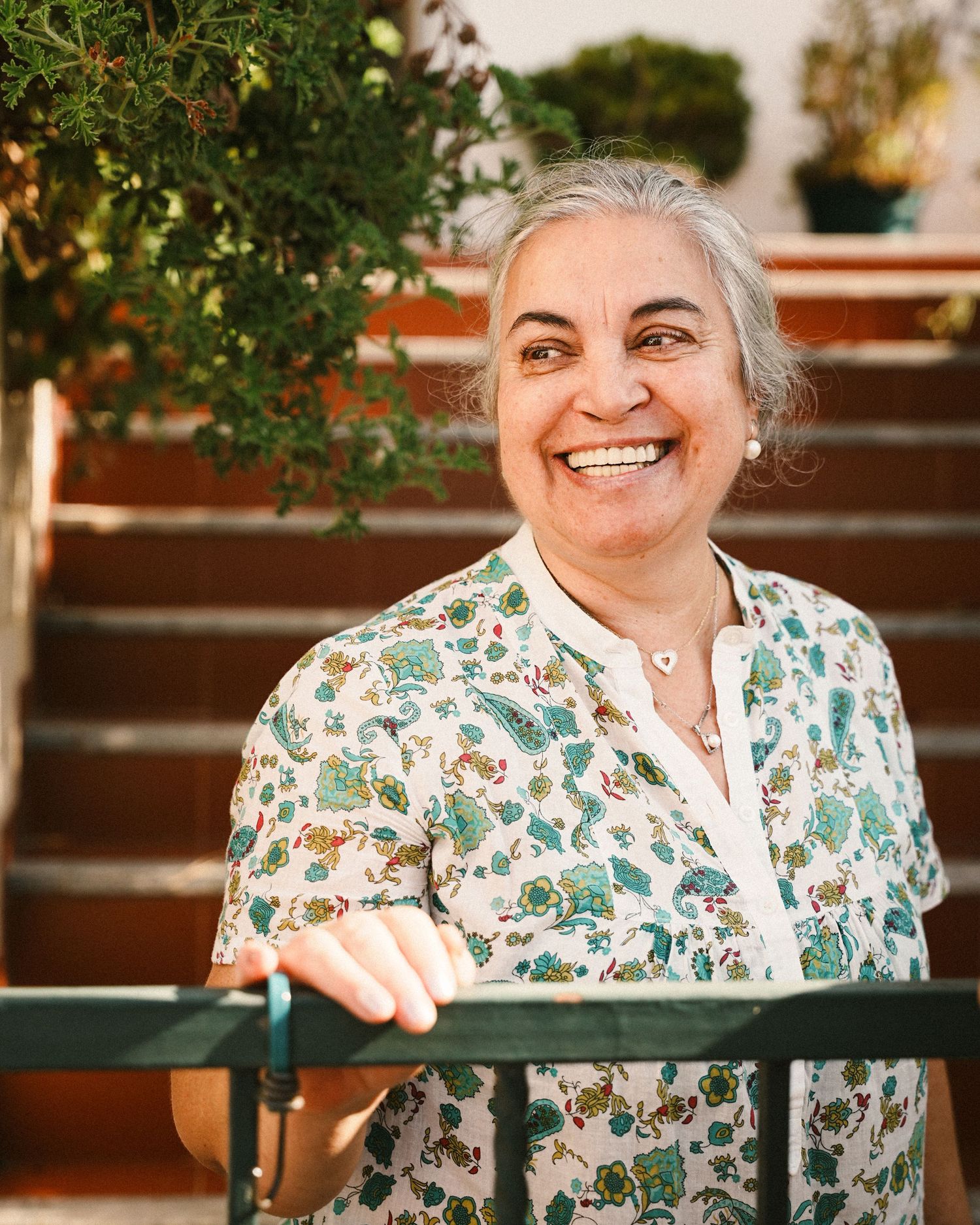 Person in a floral print top sitting outdoors on a sunny day.