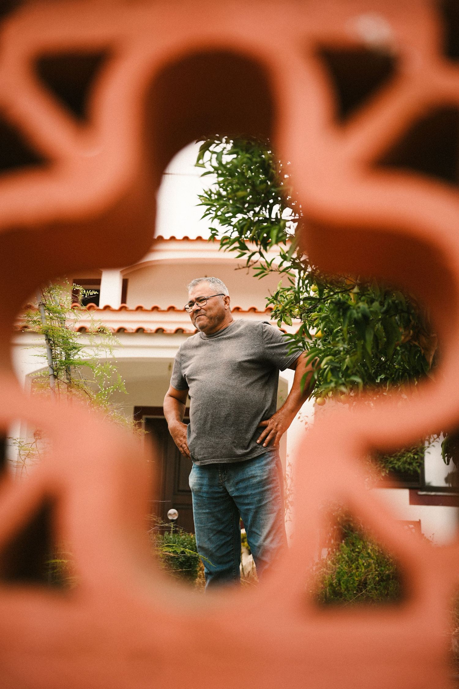 View through decorative metal railing showing someone standing near a white building.