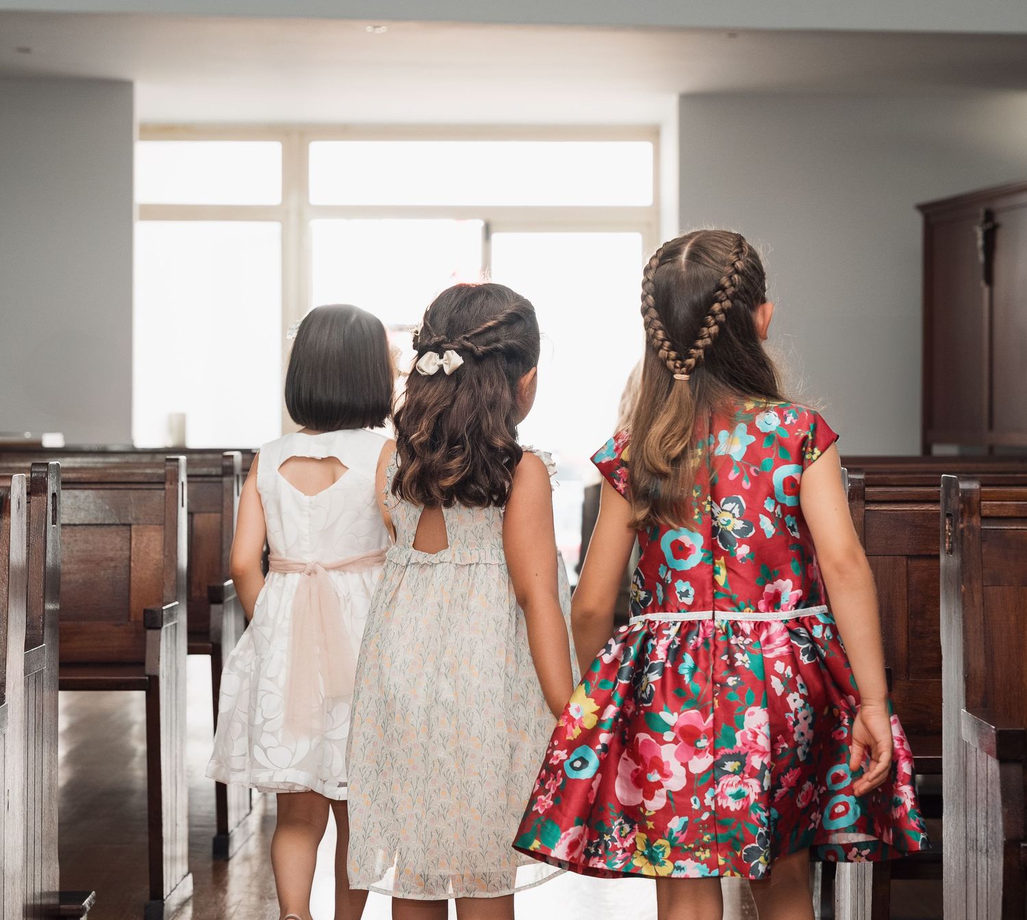 A group dressed in floral and white dresses stands in a church hallway.