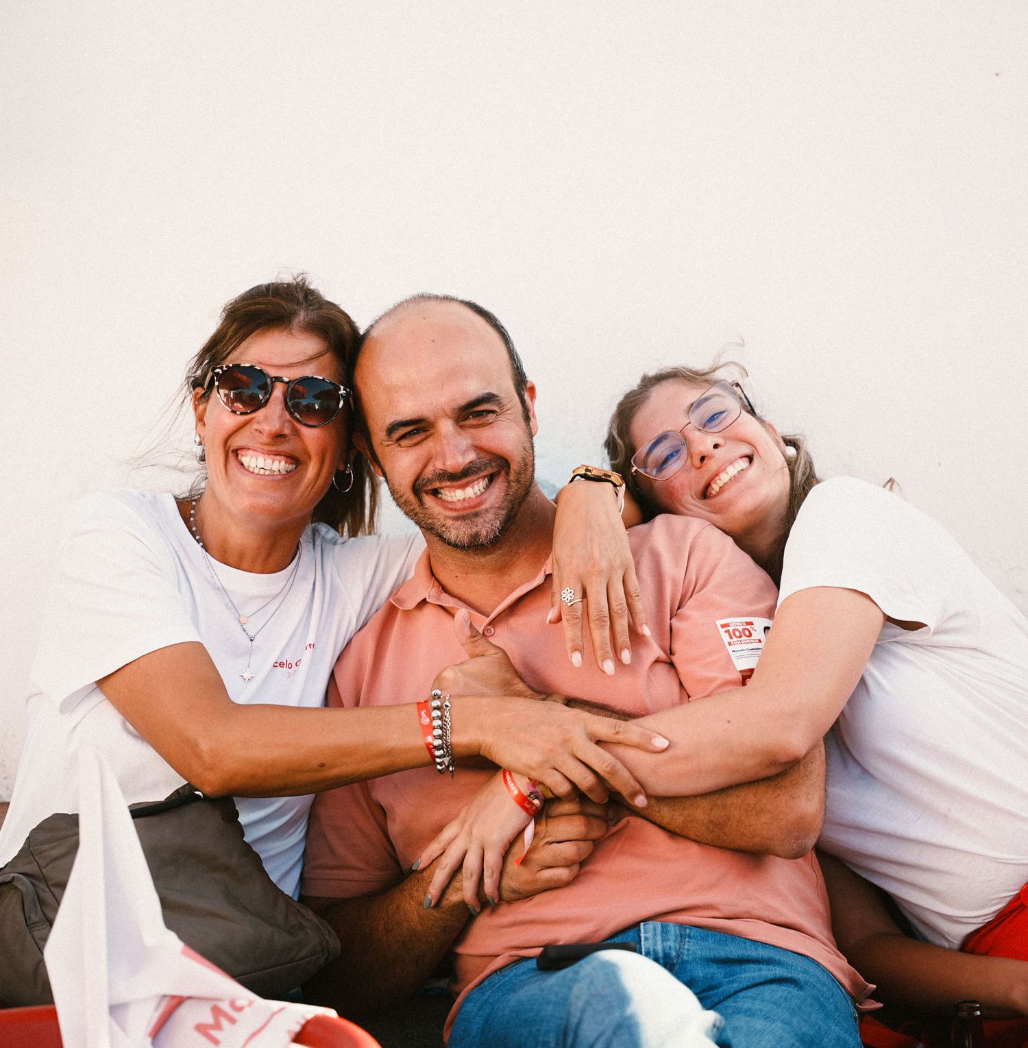 Group laughing and embracing while sitting together on a bright sunny day.