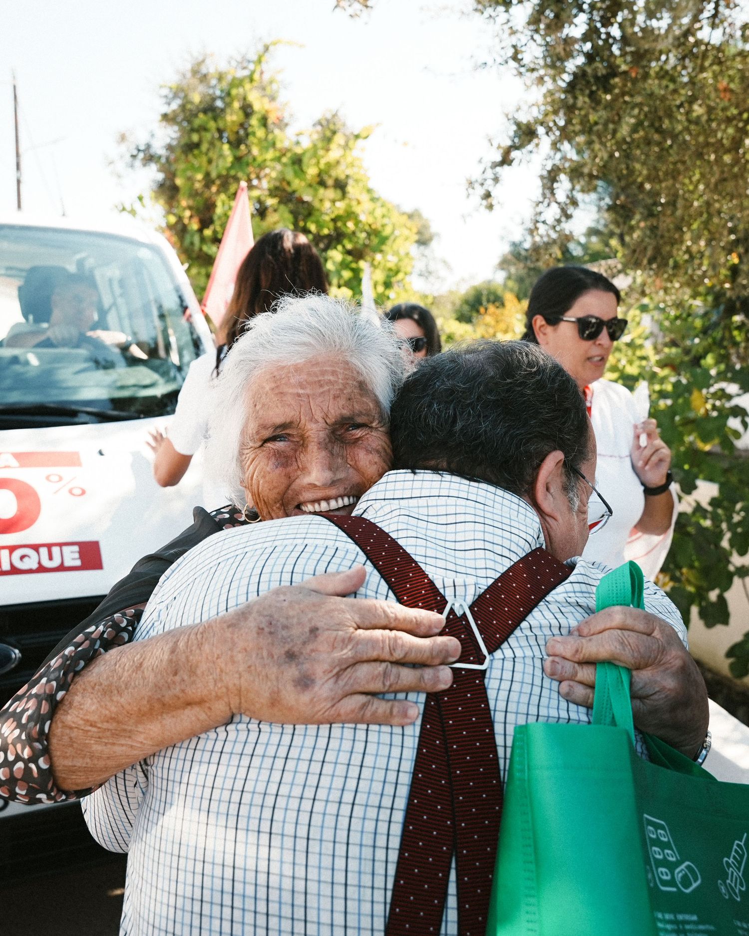 People embracing and sharing warm hugs at an outdoor community event.