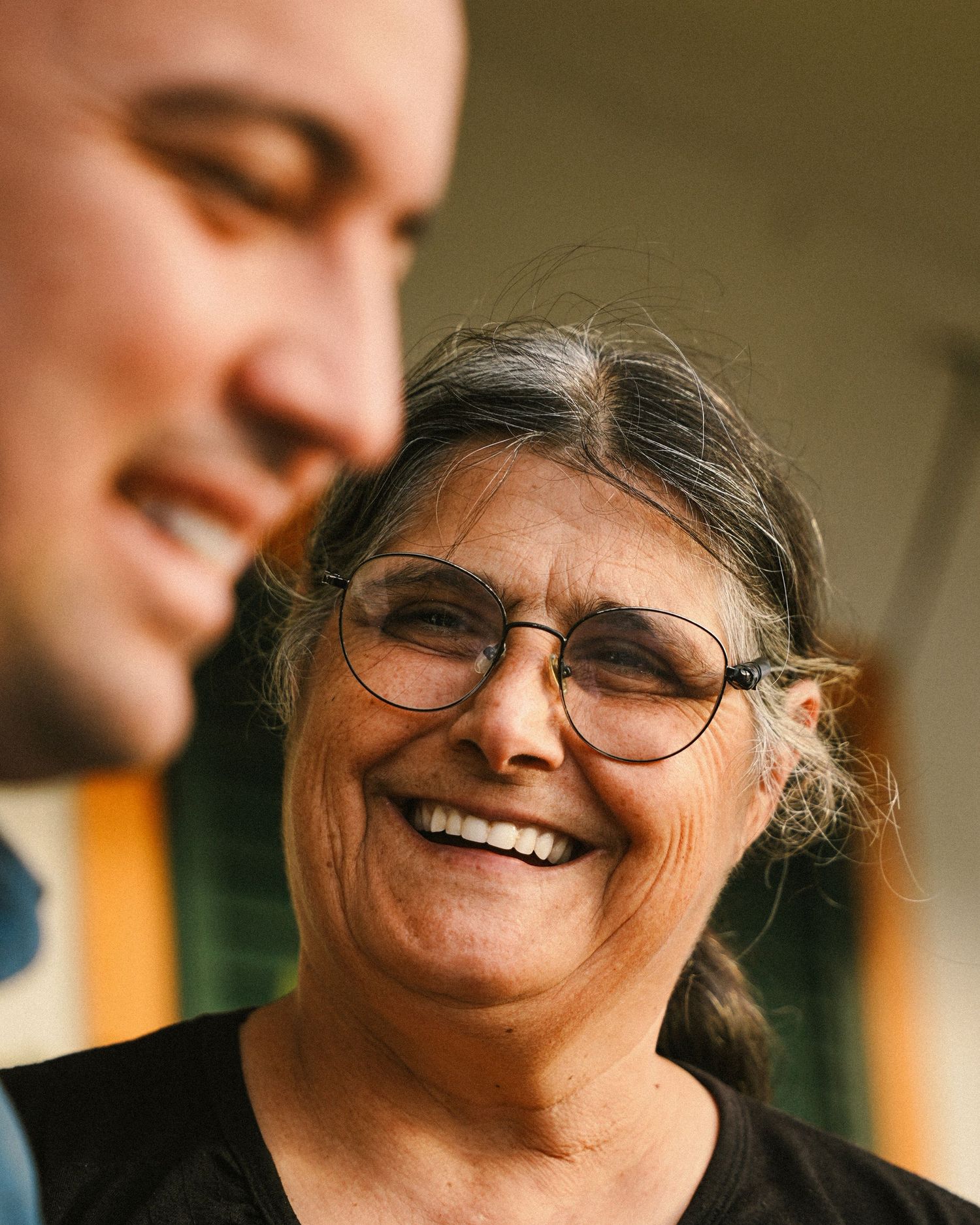 Close-up portrait of person with glasses smiling warmly in indoor setting.