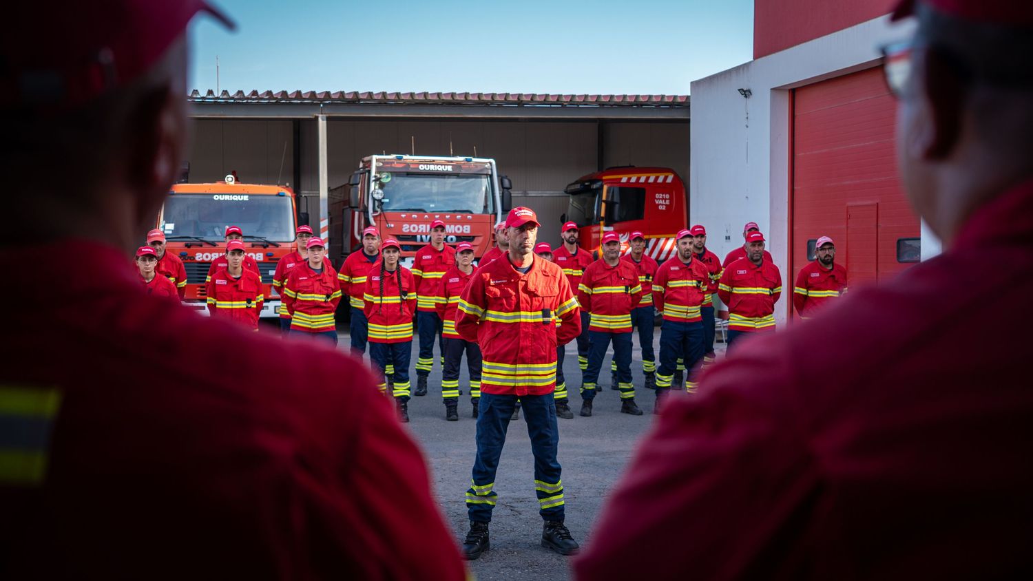 Fire station panorama showing emergency vehicles and personnel in formation.