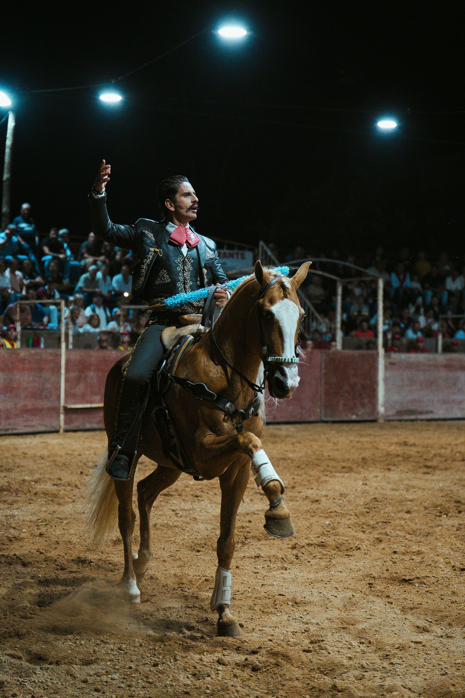 Horseback riders performing in a nighttime rodeo arena.