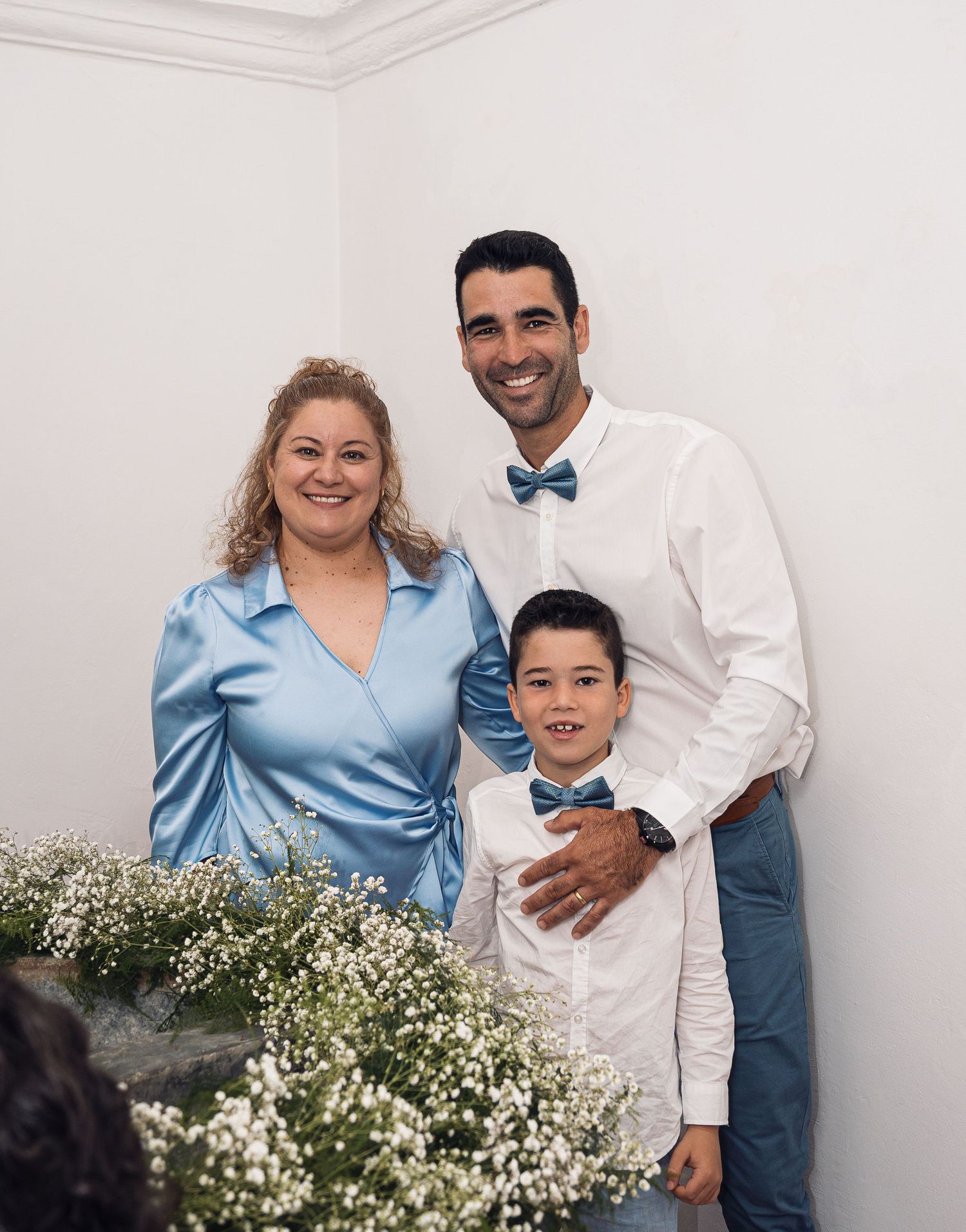 Family portrait session with blue and white coordinated outfits against a floral backdrop.