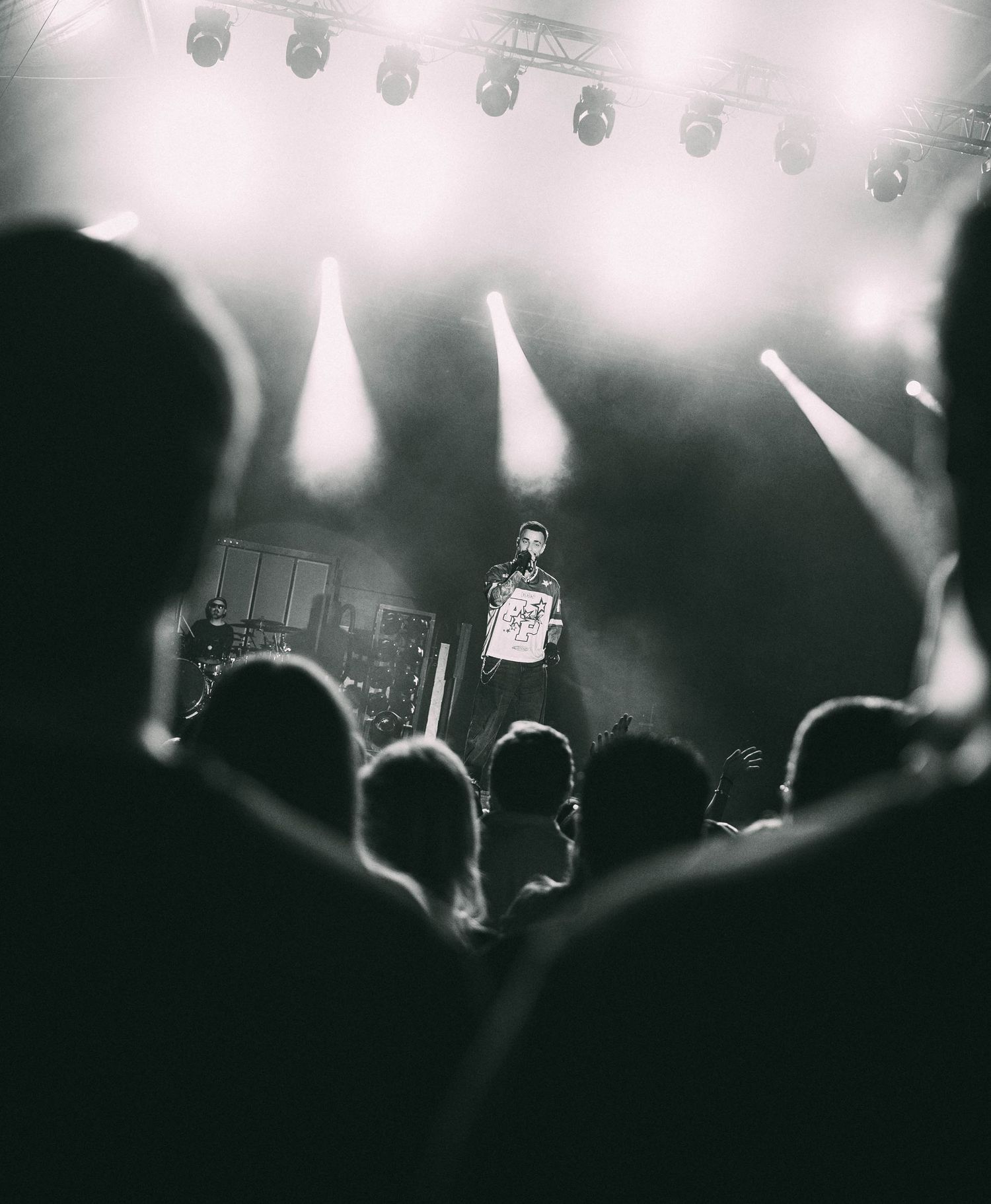 Black and white concert photo showing performer on stage with dramatic lighting.
