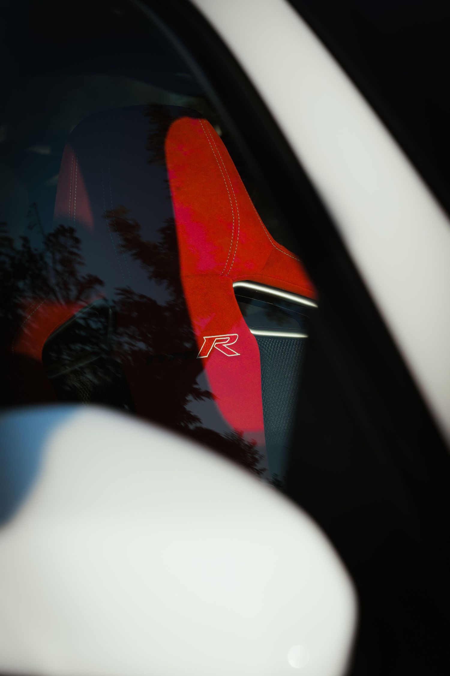 Red Type R logo reflection visible through tinted car window.