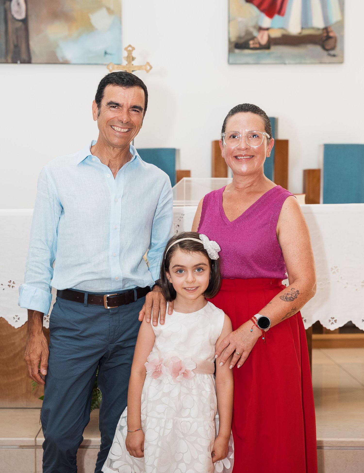 Family members pose together in a church interior with white walls and artwork.
